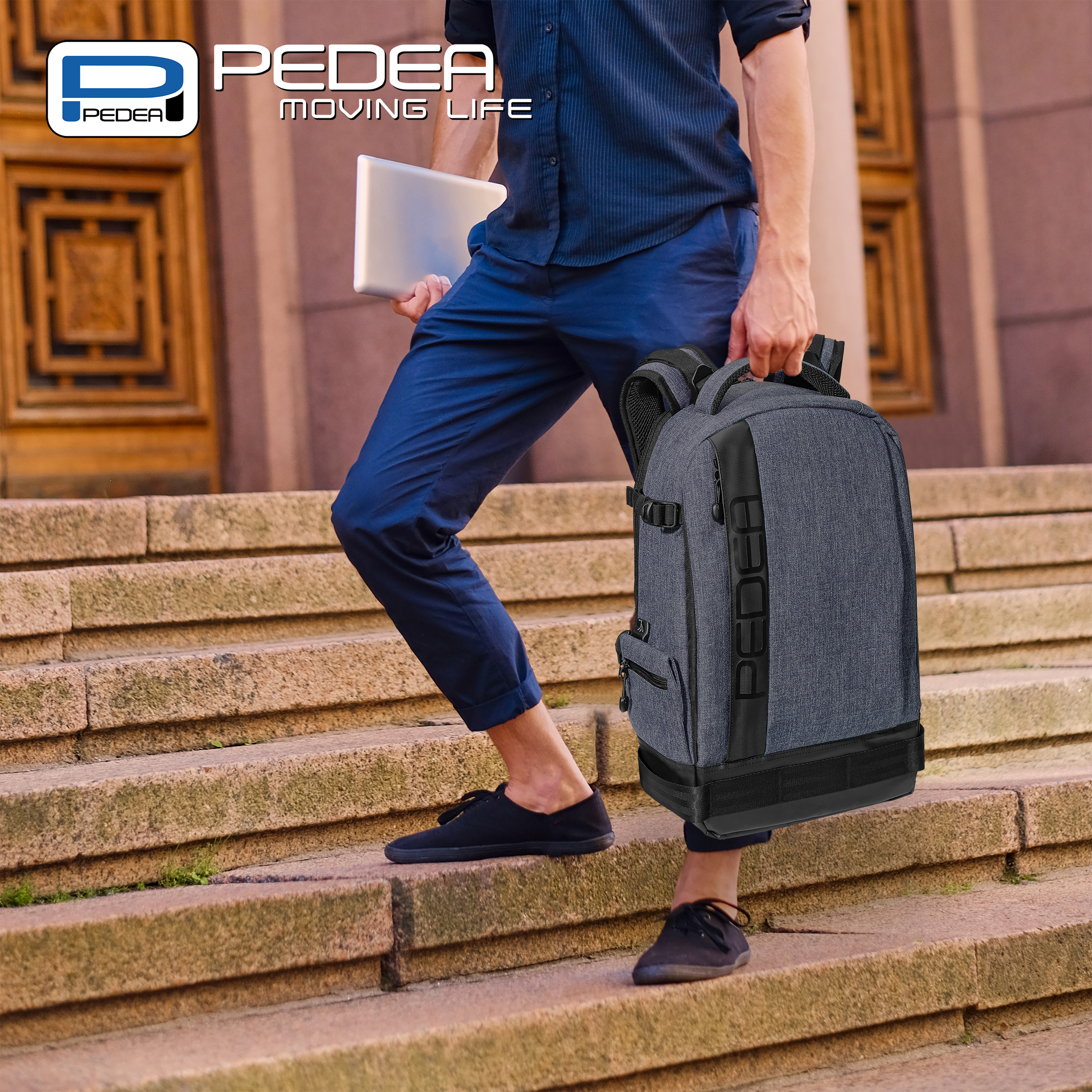 Mann geht Treppe hoch, trägt grauen Rucksack und Tablet. Gebäude im Hintergrund.