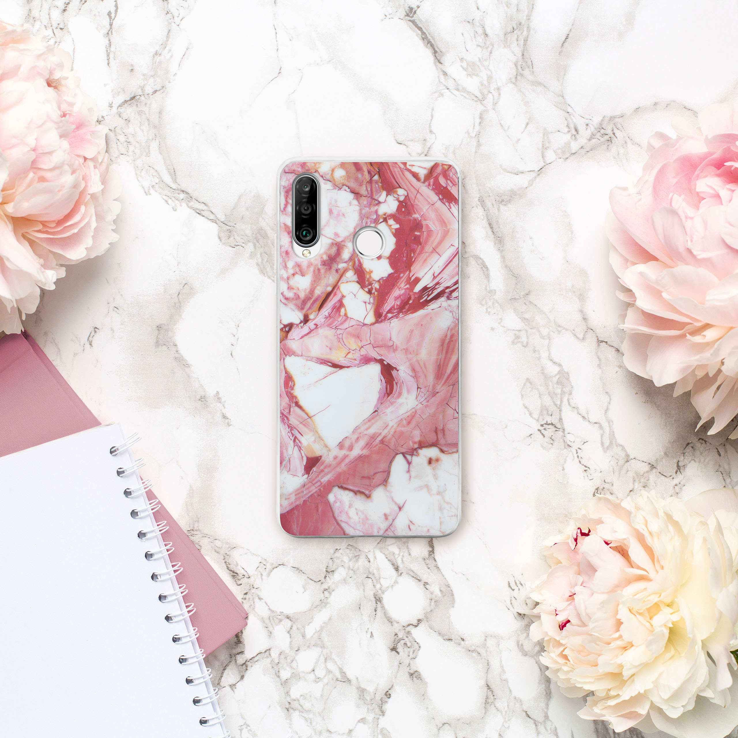 Handyhülle mit Marmormuster und Blumen, umgeben von Pfingstrosen, Notizbüchern und einem Stift.