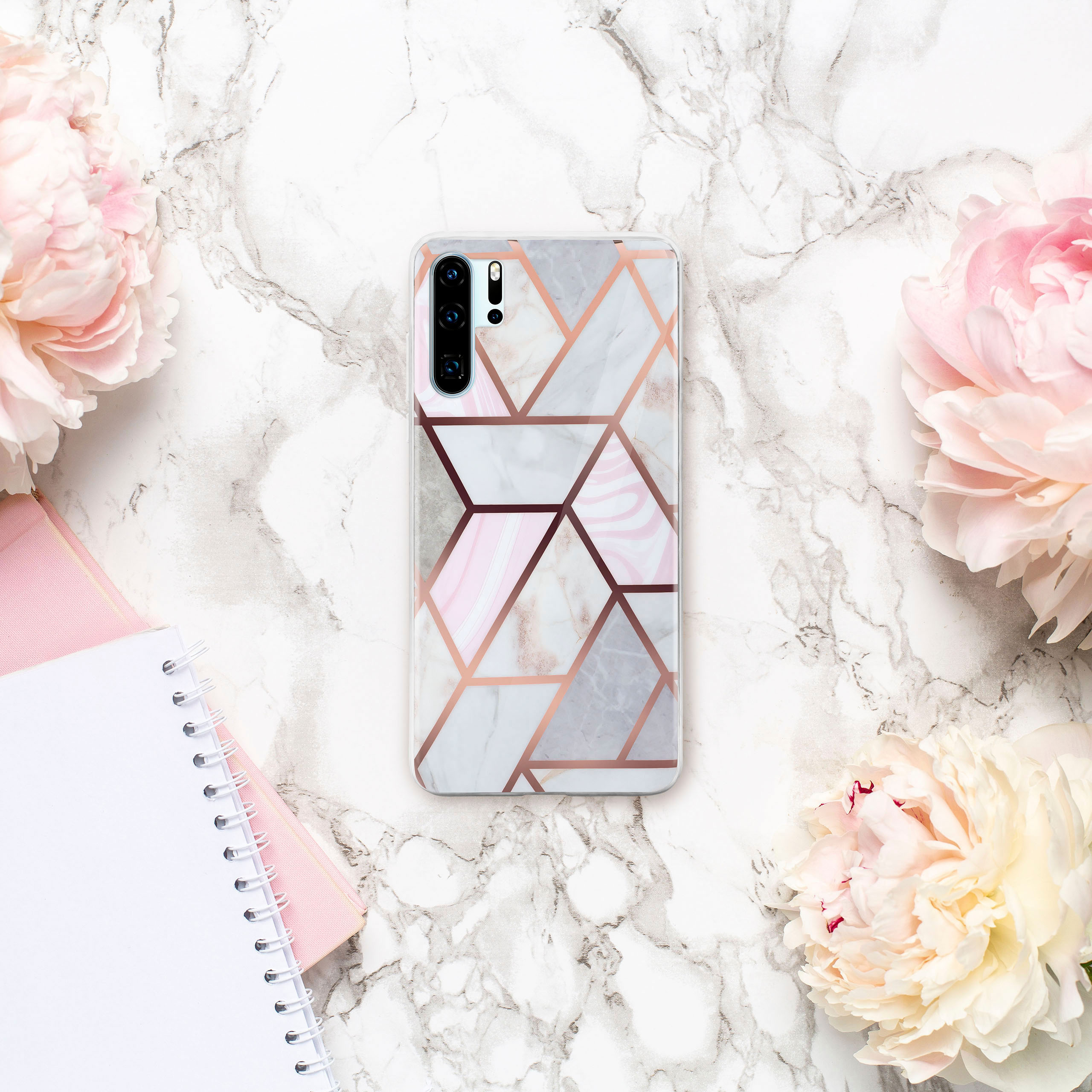 Eine Handyhülle mit Marmor-Design, rosa Akzenten und Blumen drumherum.