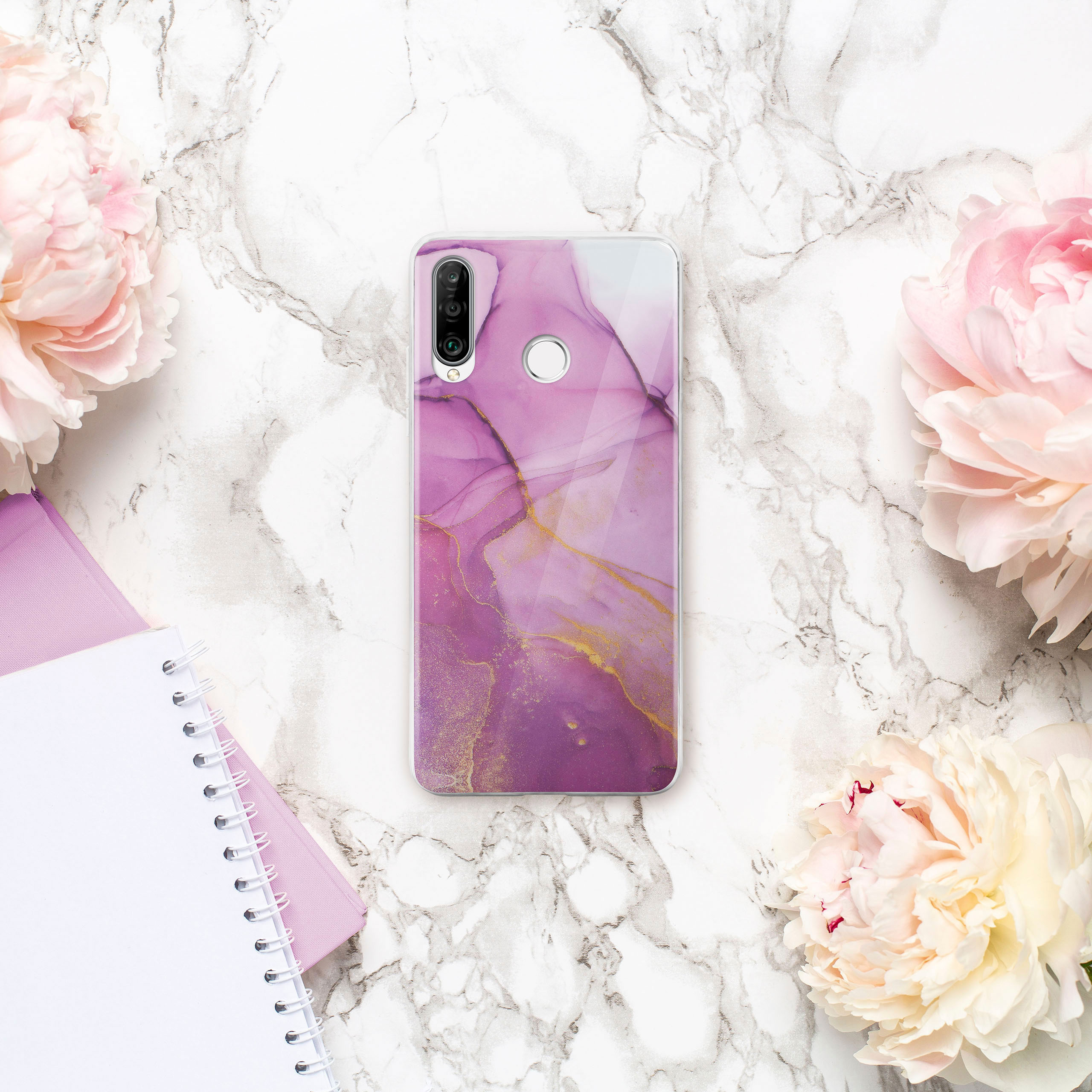 Handyhülle mit rosa Marmordesign, umgeben von Blumen und Notizbüchern auf Marmoroberfläche.