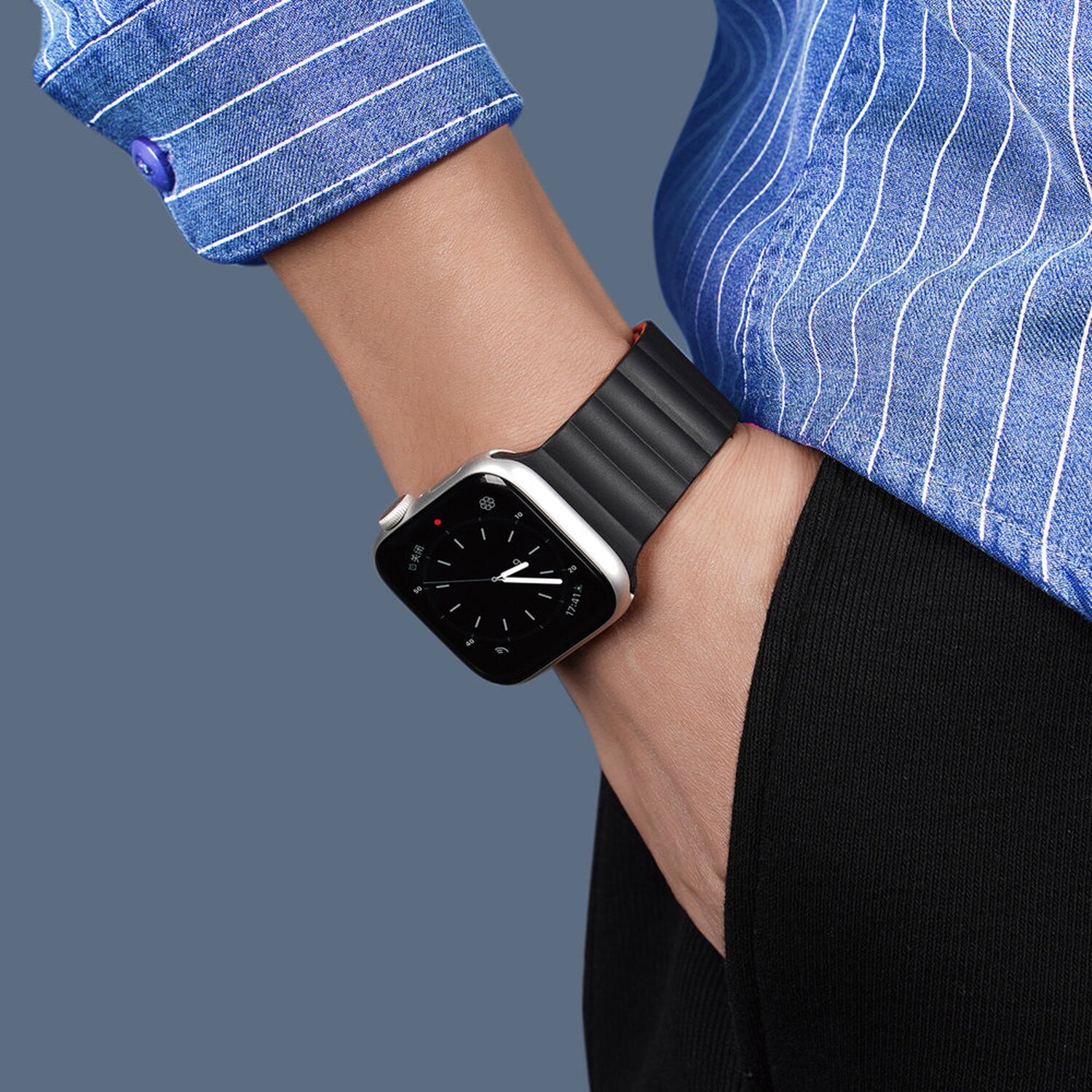 Eine Person, die eine Smartwatch mit schwarzem Armband am Handgelenk trägt.