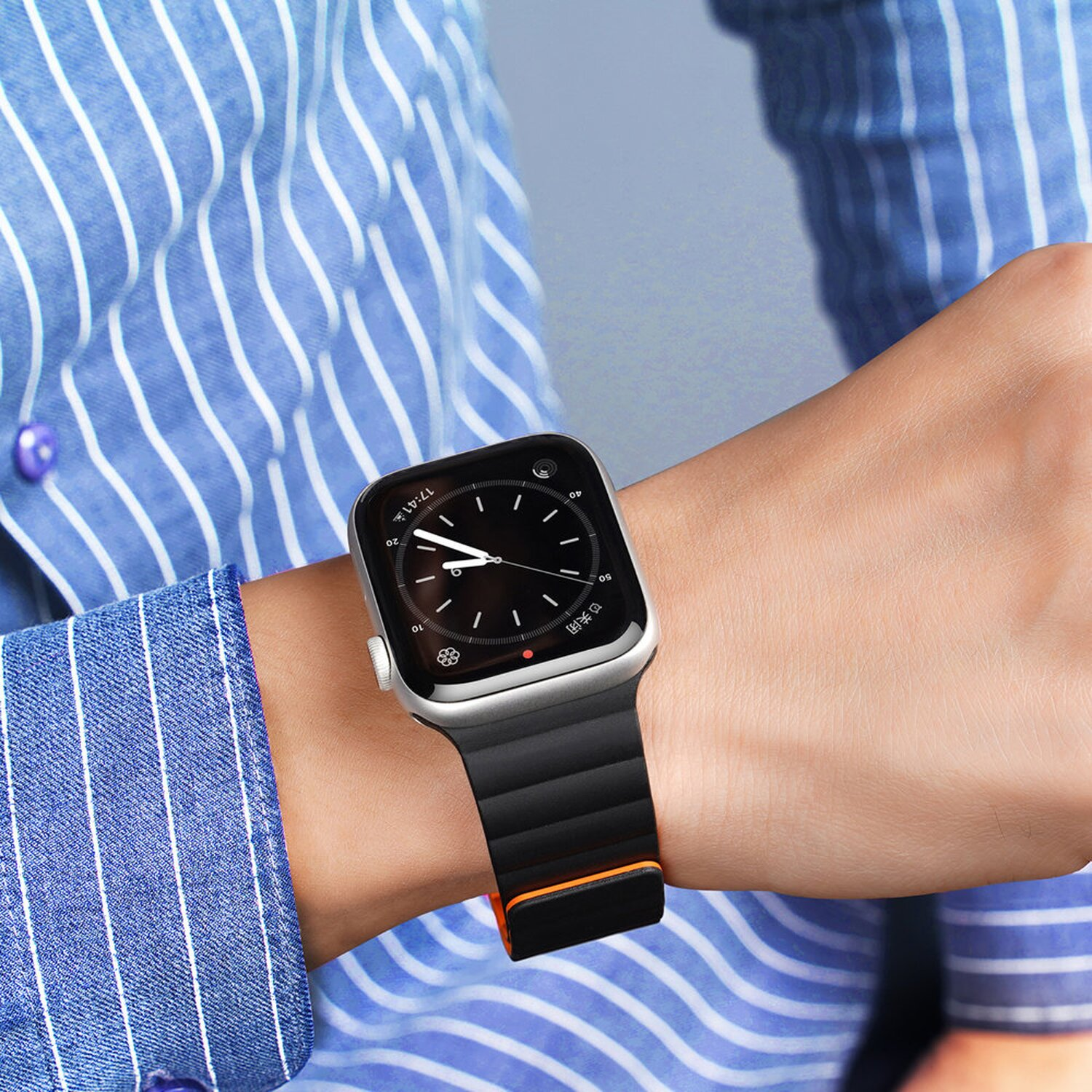 Mannes Handgelenk mit schwarzer Uhr und schwarz-orangefarbenem Armband.
