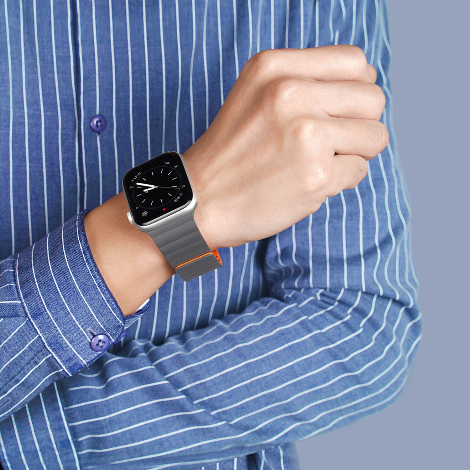 Das Handgelenk einer Person mit einer Smartwatch. Die Uhr hat ein graues Armband mit orangenem Akzent.