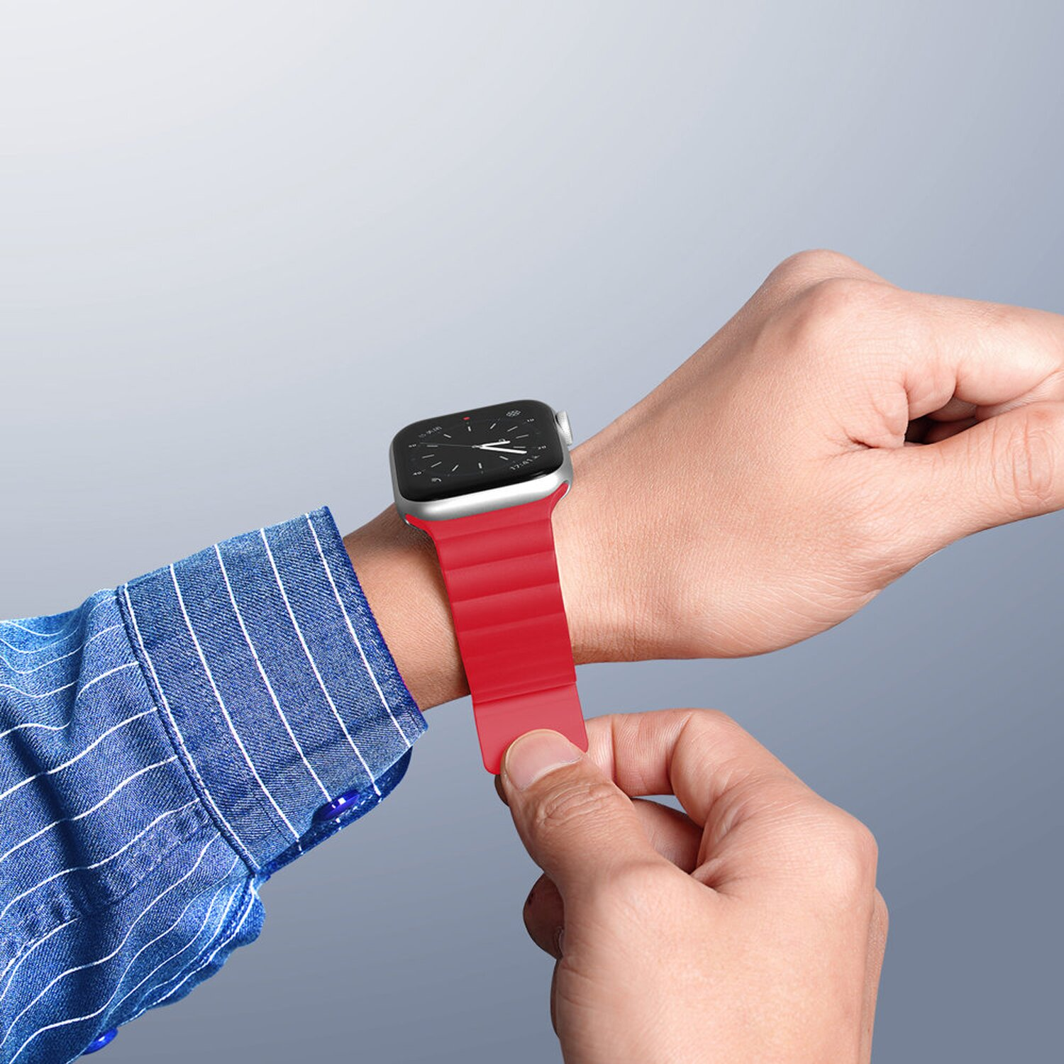 Person trägt ein rotes Uhrenarmband an ihrem Handgelenk. Sie tragen ein blaues Hemd.