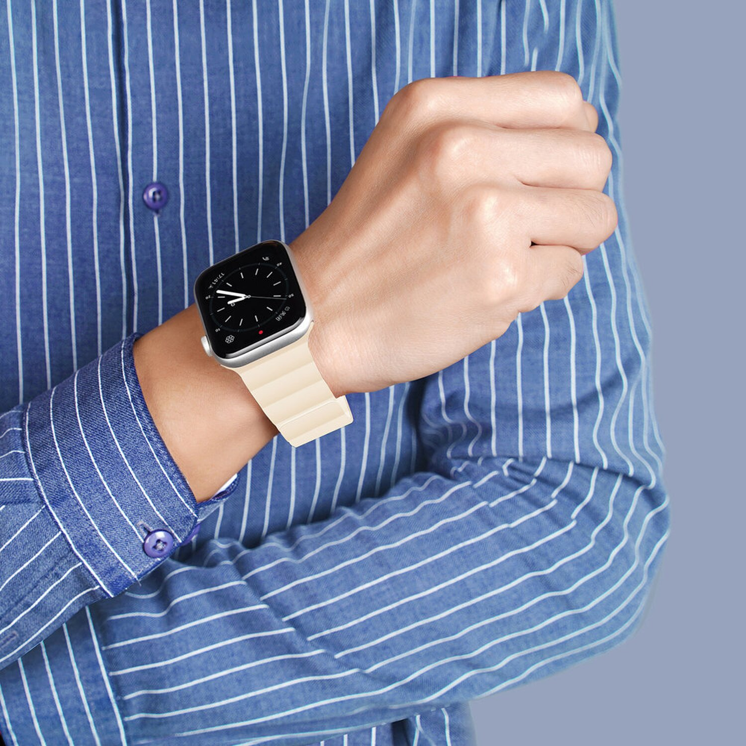 Ein Mann trägt ein blau gestreiftes Hemd, eine Uhr mit cremefarbenem Armband an seinem Handgelenk.