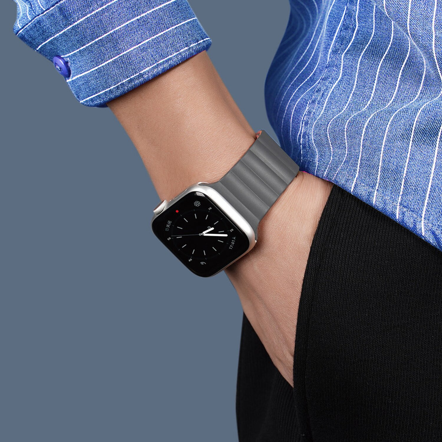Eine Person, die eine silberne Apple Watch mit einem grauen Sportarmband trägt.