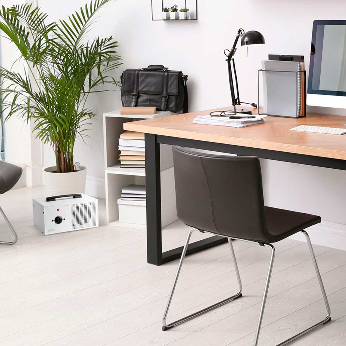 Configuración de escritorio de oficina con planta, computadora, lámpara y silla. Suelo y paredes blancos, luz natural.