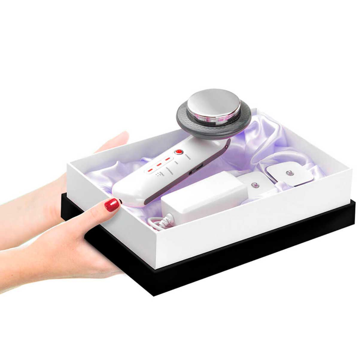 Manos sosteniendo una caja de regalo con un dispositivo para el cuidado de la piel dentro. Caja blanca, base negra y cinta rosa.