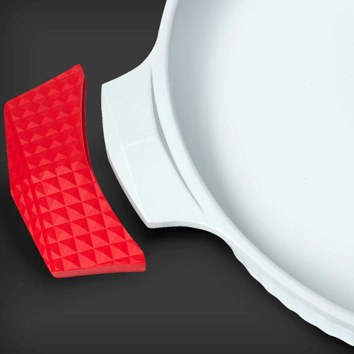 Una pieza de esquina triangular roja junto a un plato blanco y redondo sobre un fondo negro.