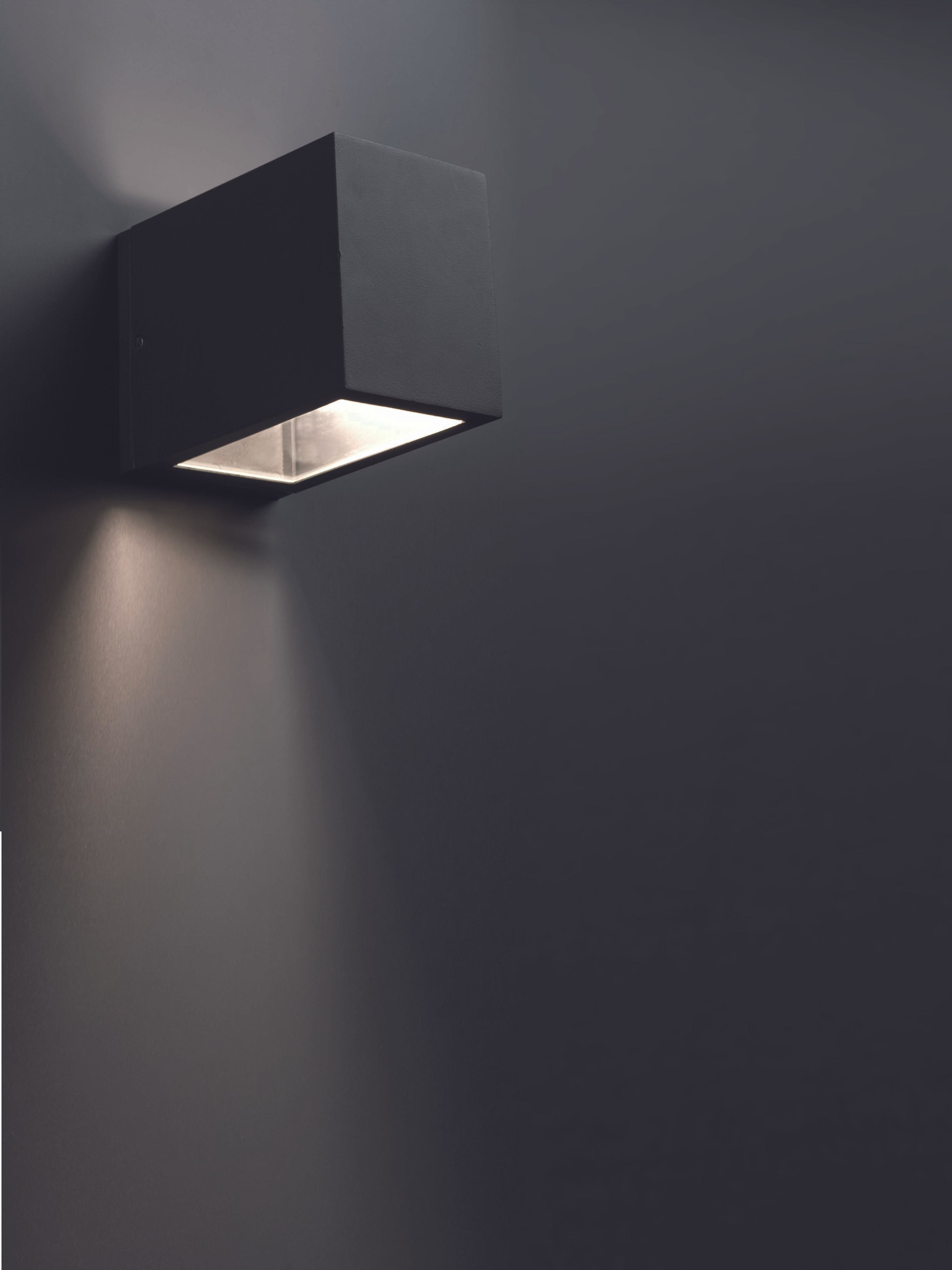 Schwarze Wandlampe. Die Lampe wirft Licht auf die Wand. Die Wand ist dunkelgrau.