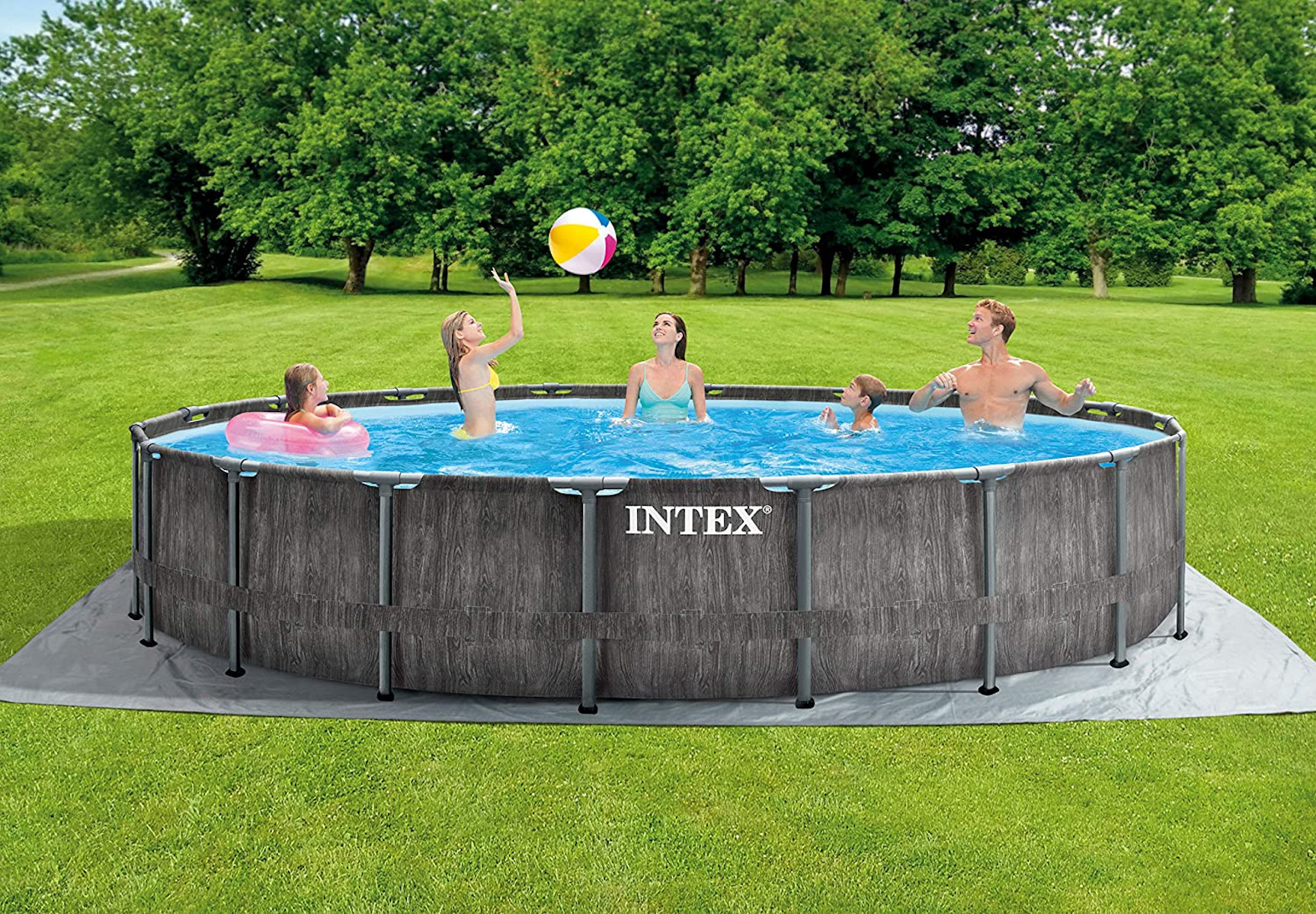 Familie im Pool, Bäume im Hintergrund. Der Pool hat graue Holztextur.