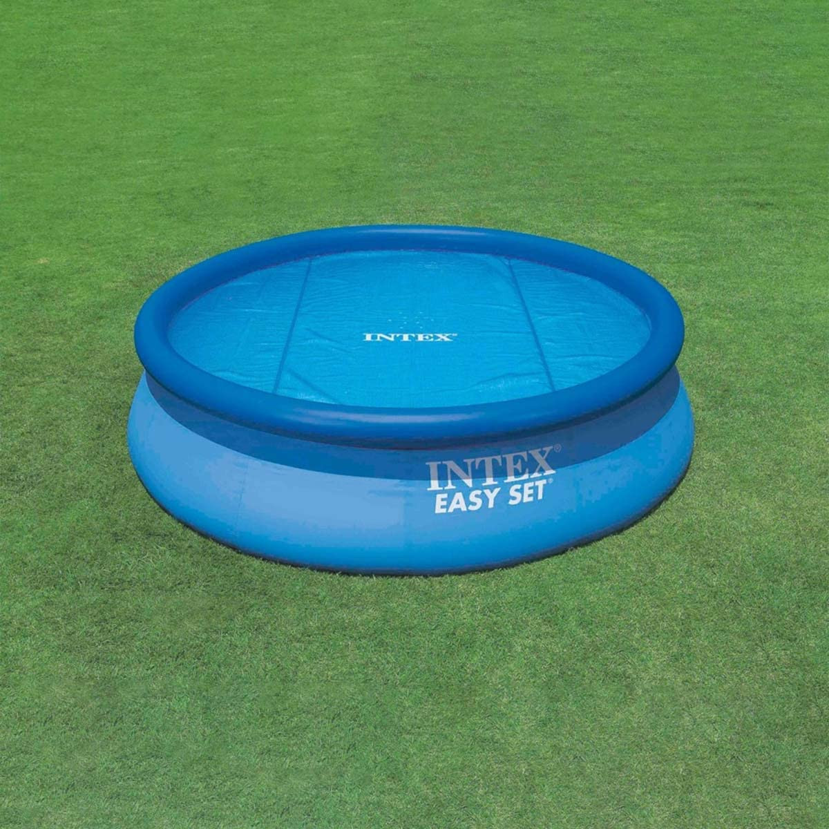 Blauer Intex Easy Set Pool mit Wasser gefüllt, mit blauer Plane bedeckt, auf einer grünen Rasenfläche.