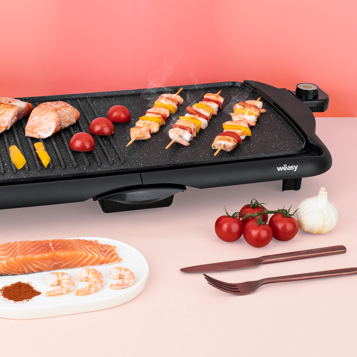 Grill mit Lachs, Spießen, Tomaten, Knoblauch und Utensilien. Rosa Hintergrund.