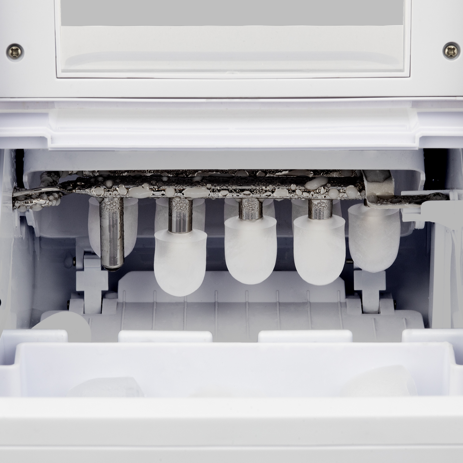 Zbliżenie wnętrza maszyny do lodu. Cylindryczne formy do lodu, białe elementy plastikowe.