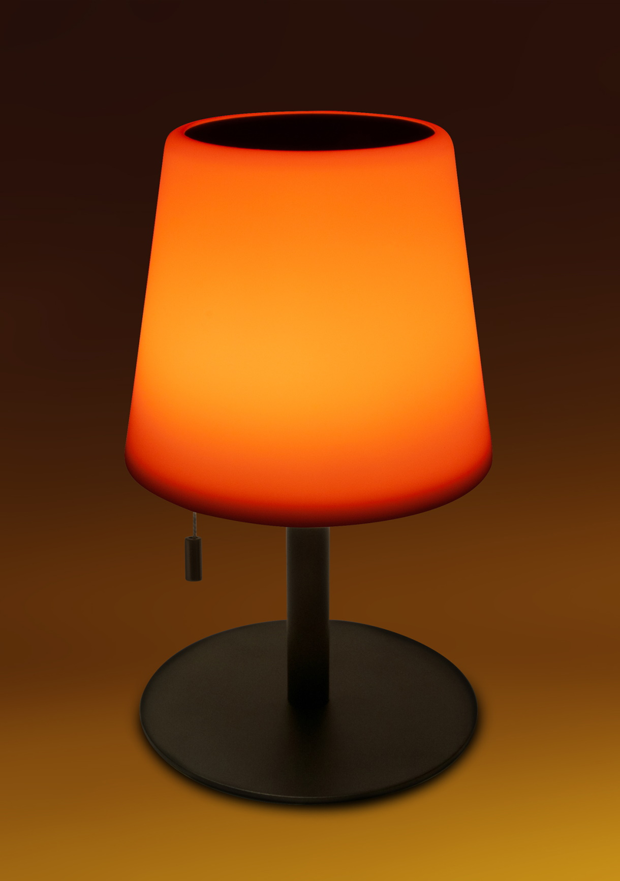 Orangefarbene Lampe mit schwarzem Sockel. Die Lampe ist beleuchtet.