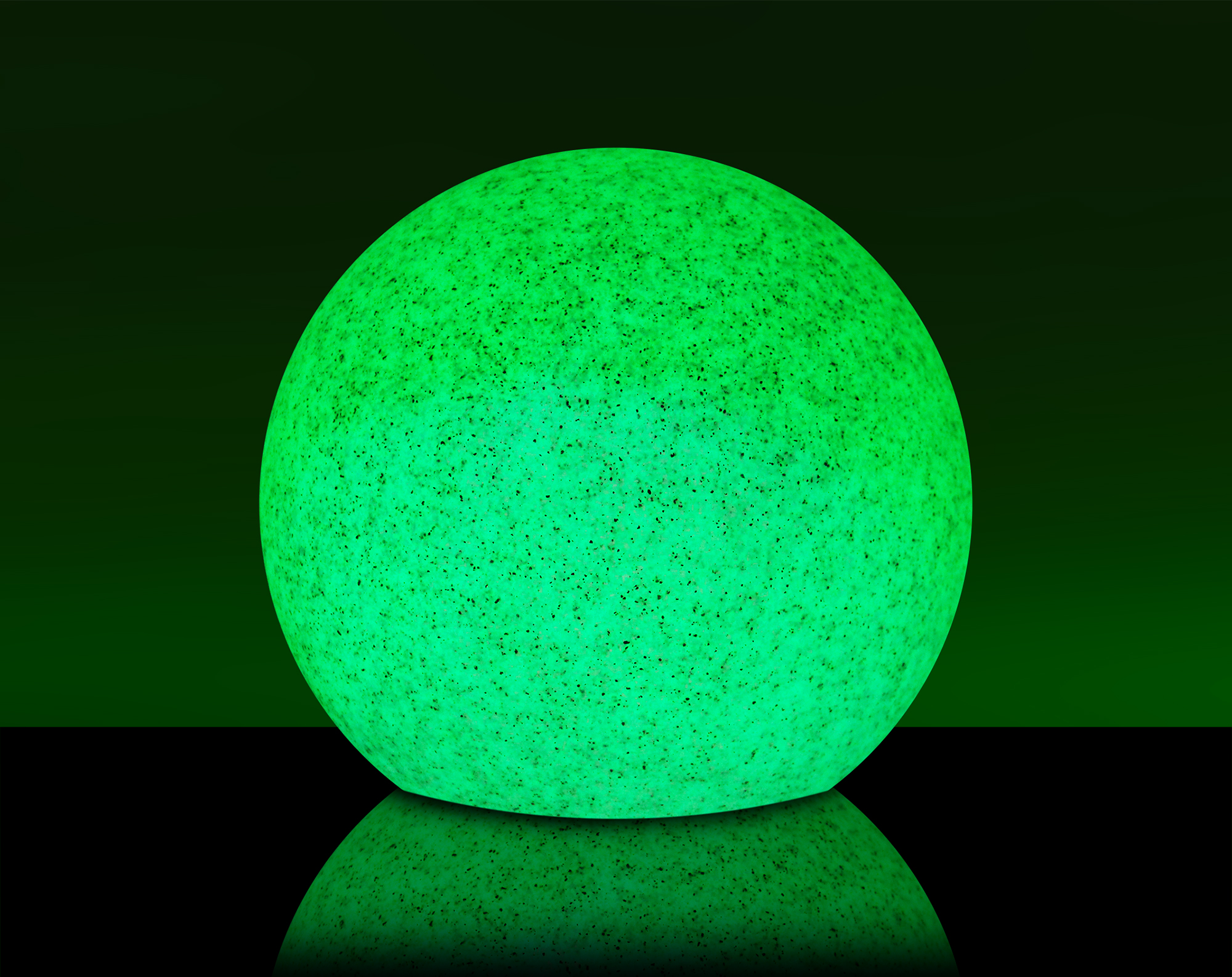 Grün leuchtender Ball. Der Ball liegt auf einer schwarzen Oberfläche. Dunkelgrüner Hintergrund.
