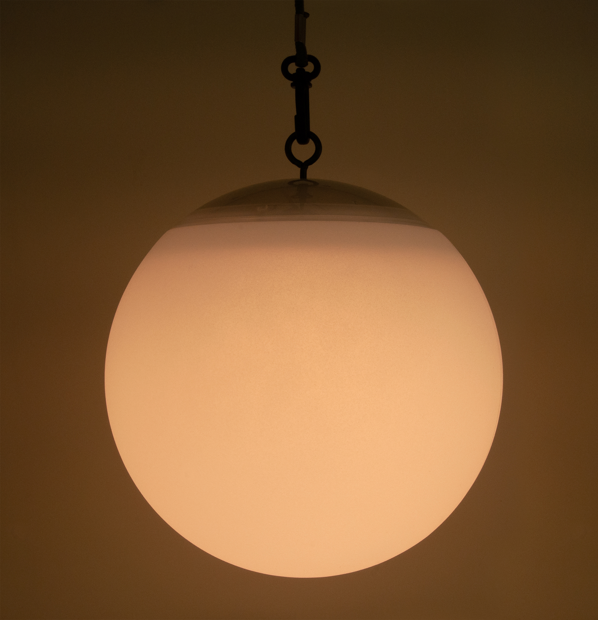 Hängende Kugelleuchte. Opakes weißes Glas. Dunkler Hintergrund. Warmer Glanz.