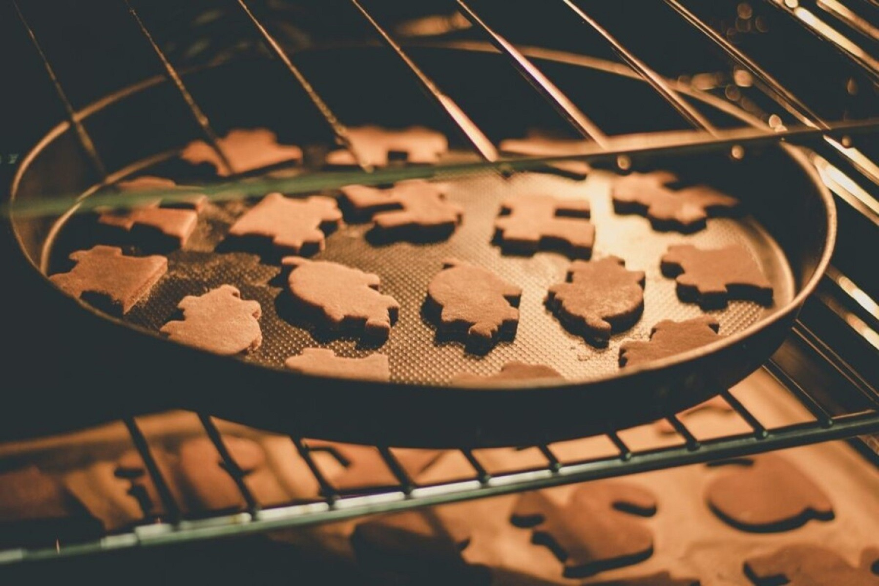 Un horno con una bandeja de galletas de jengibre en forma de piezas de rompecabezas.