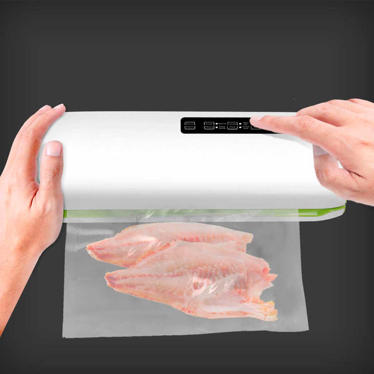 Manos usando selladora al vacío blanca para sellar dos filetes de pescado crudo en bolsa plástica.