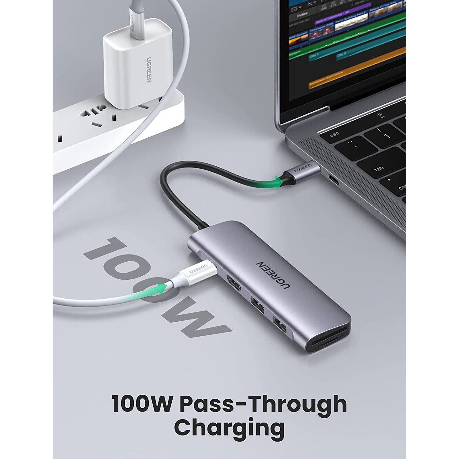 Srebrny hub USB podłączony do laptopa, z ładowarką w pobliżu.