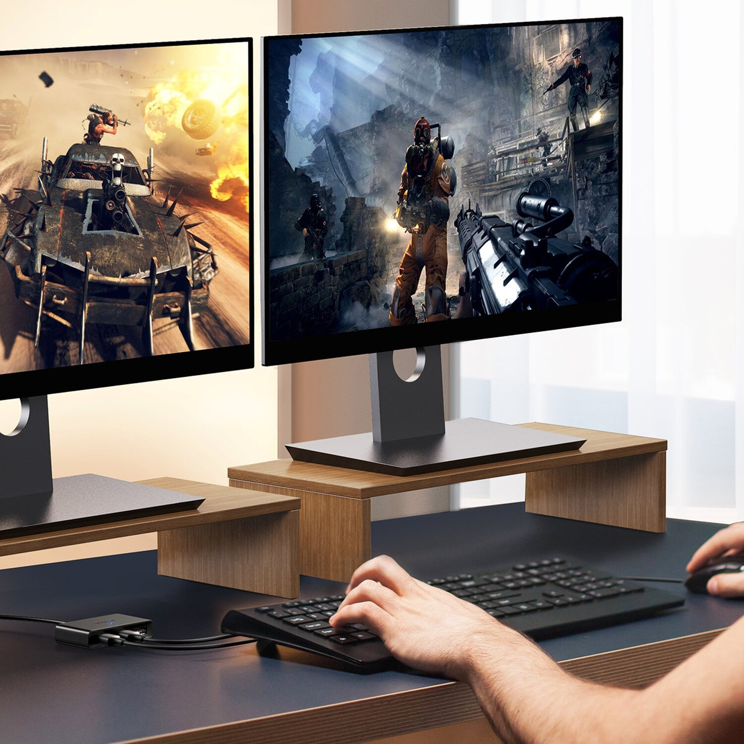 Due monitor mostrano un videogioco, tastiera, mouse e hub USB su una scrivania.