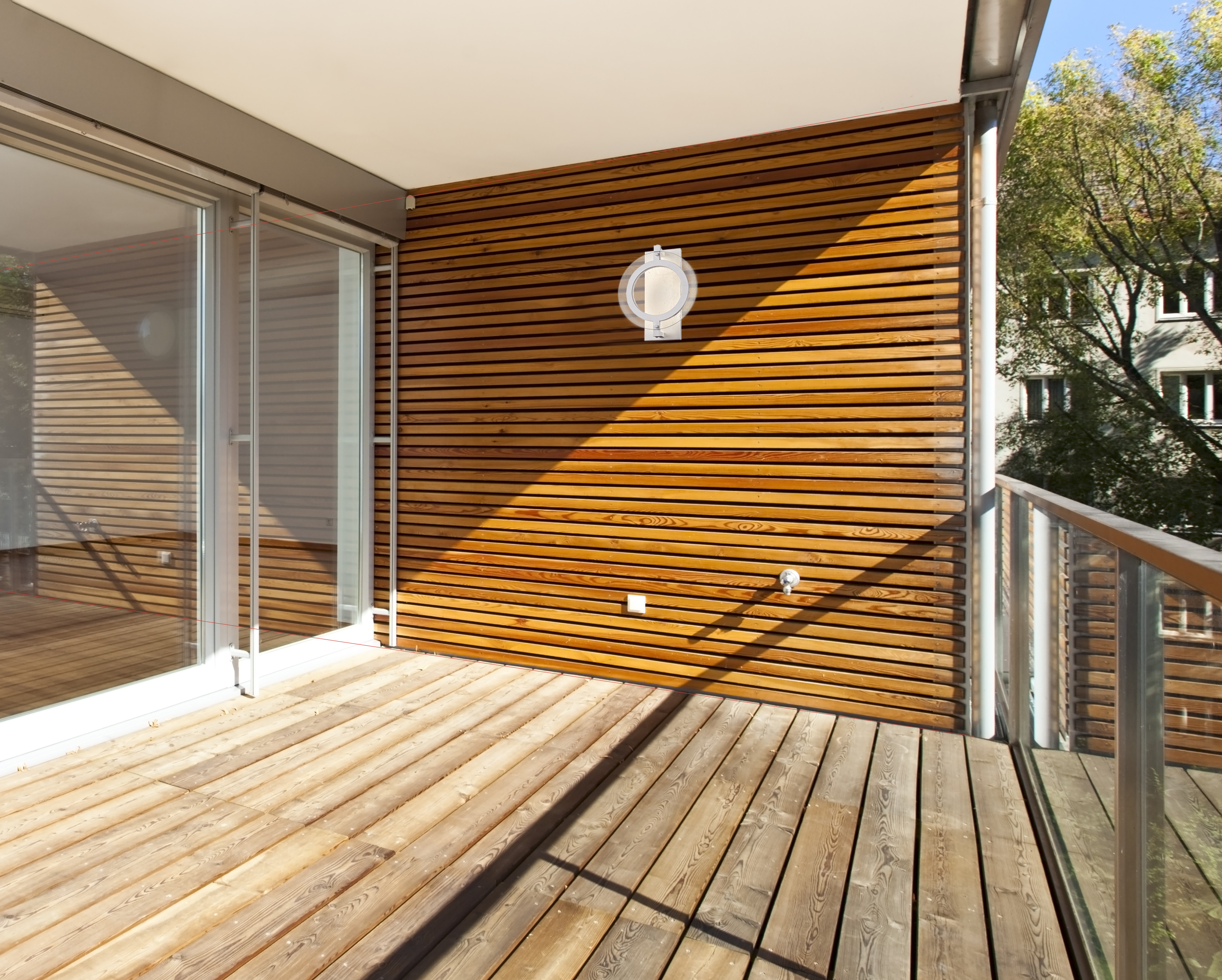 Holzbalkon mit Holzboden, Holzwand mit weißer Lampe und Glastür.
