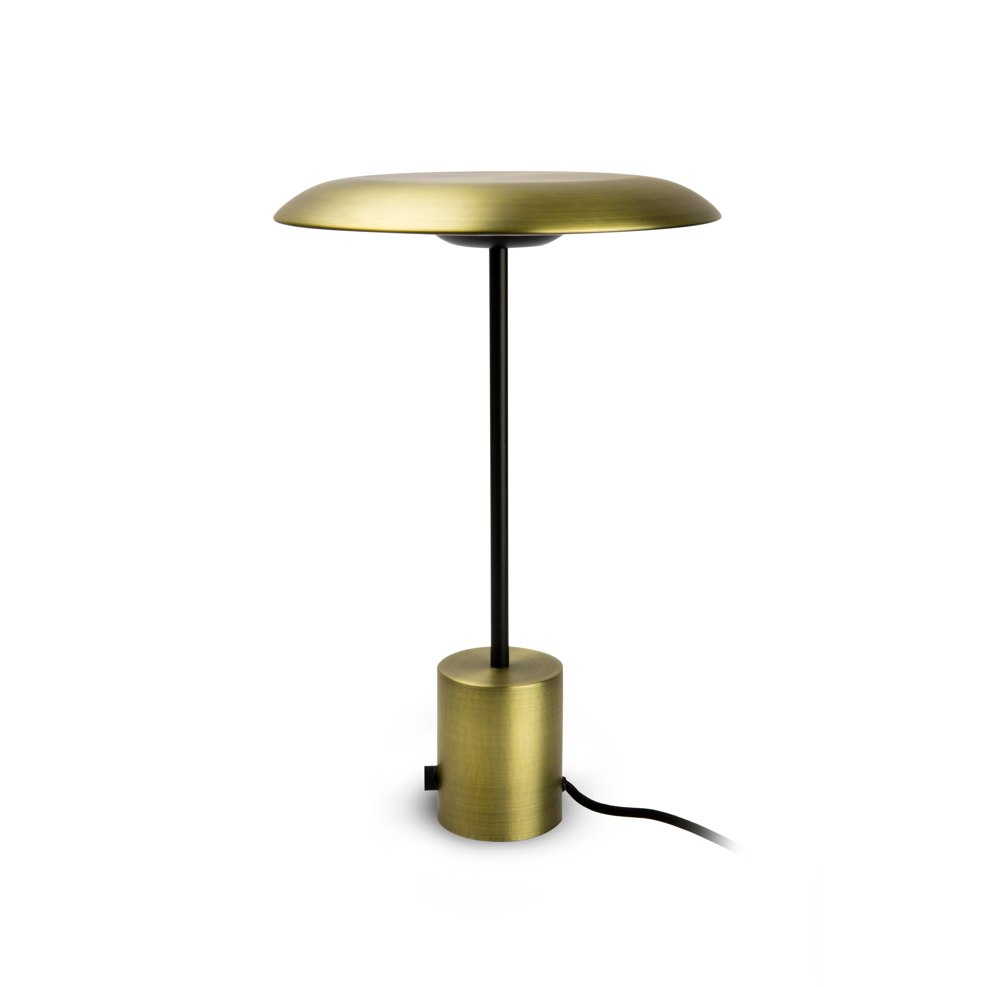 Lampada da tavolo dorata con stelo nero e base cilindrica. Su sfondo bianco.