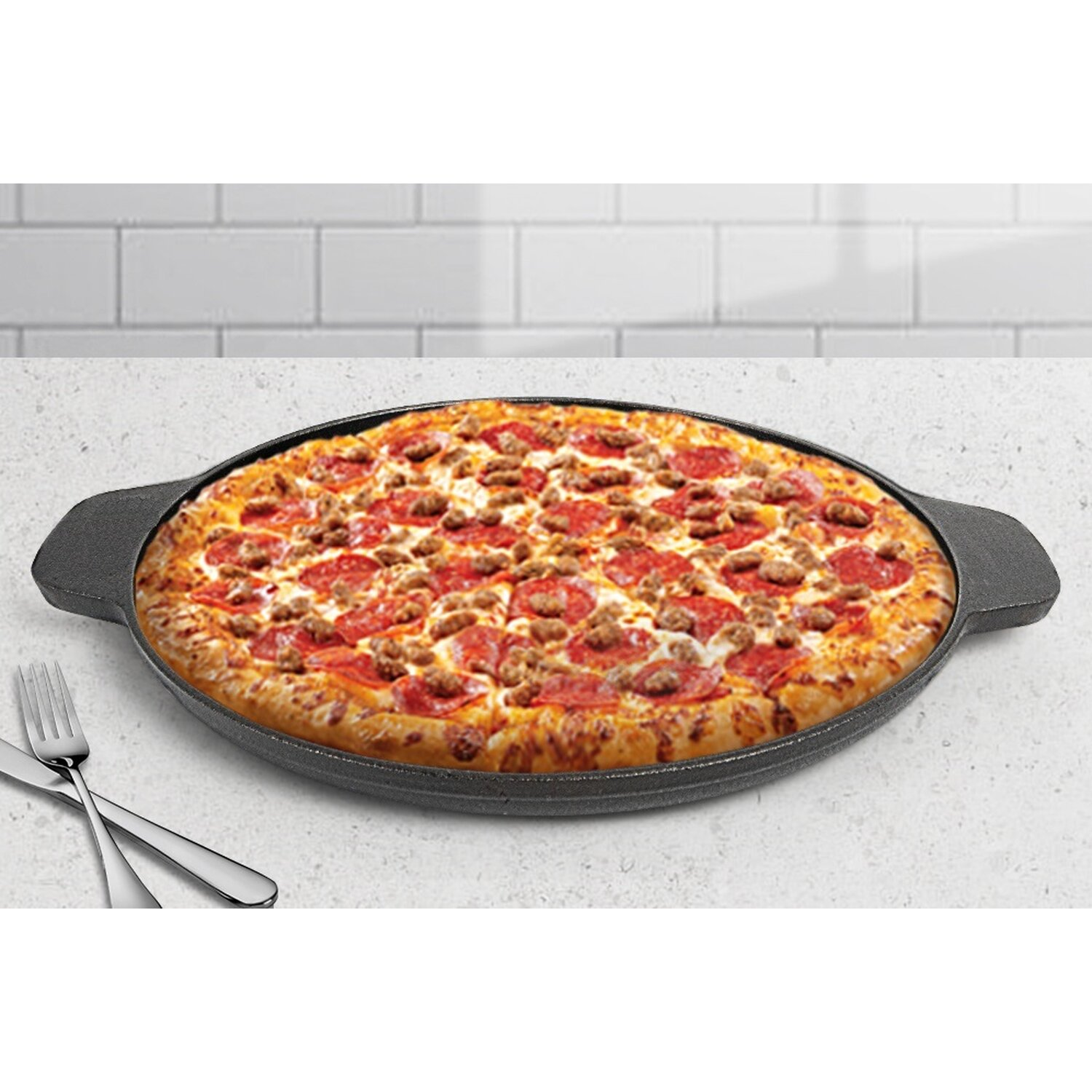 Eine Pizza in einer schwarzen Pfanne mit Wurst und Peperoni. Gabel und Messer liegen daneben.