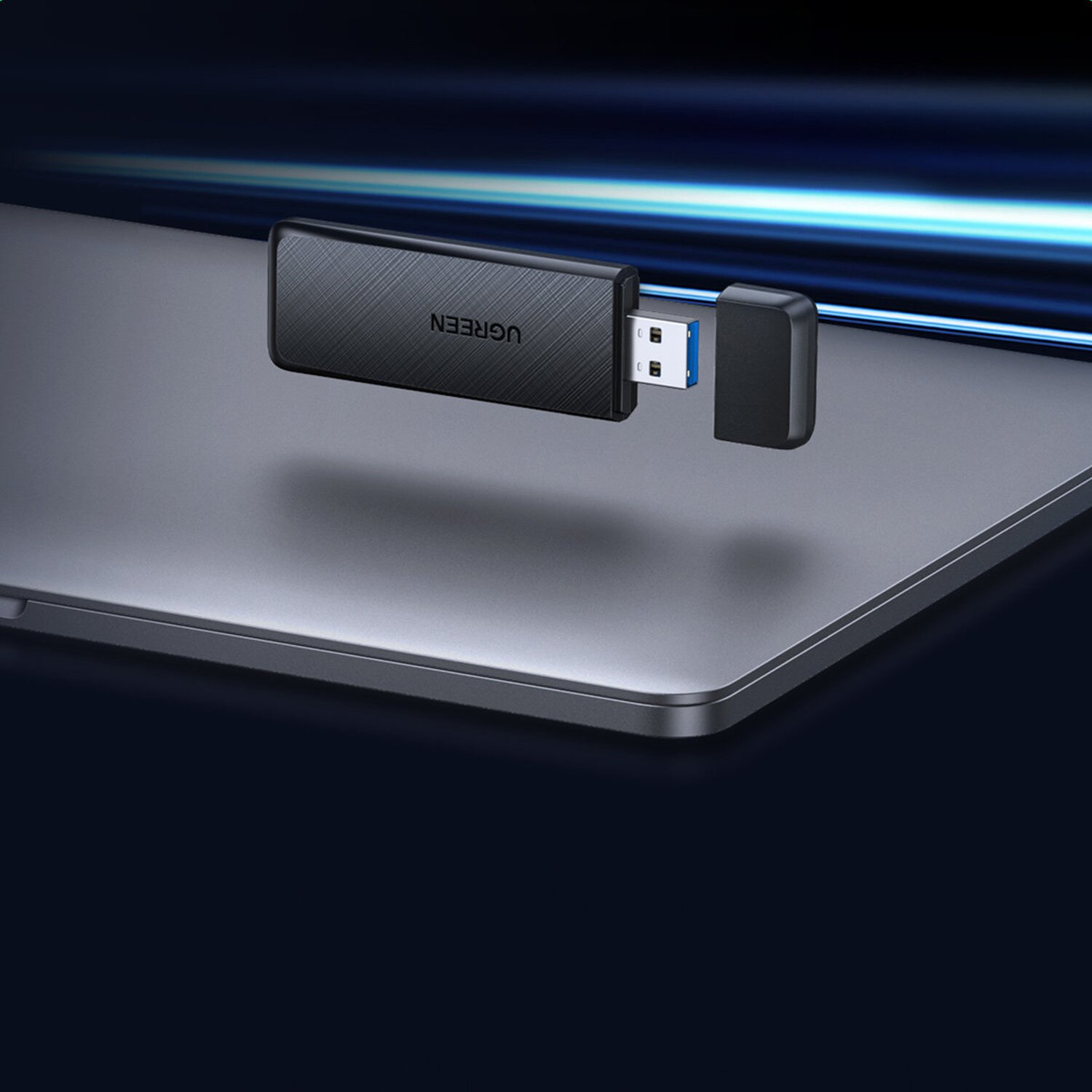 Schwarzer UGREEN USB-Dongle, der in einen silbernen Laptop eingesteckt ist.