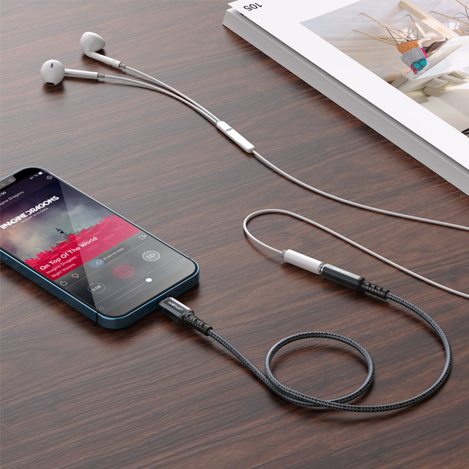 Ein Telefon, das mit Kopfhörern und einem Kabel verbunden ist. Das Telefon zeigt Musik auf einem Holzgrund an.