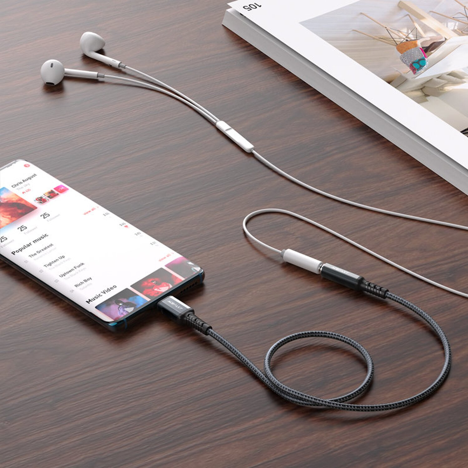 Ein Smartphone ist mit Kopfhörern mit Kabel verbunden. Das Telefon liegt auf einem Holztisch.