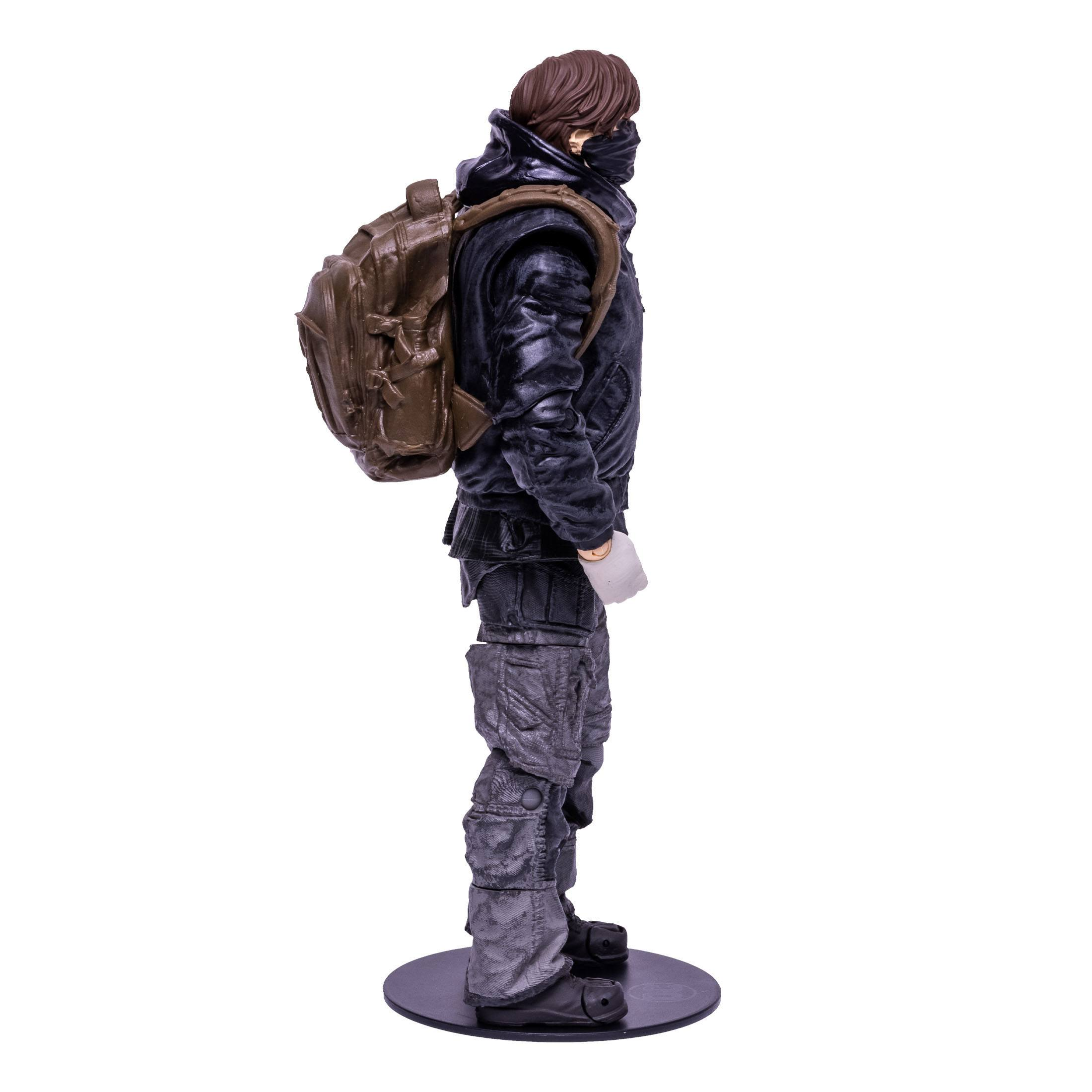 Eine Figur einer Person in dunkler Kleidung mit Rucksack, im Profil stehend.