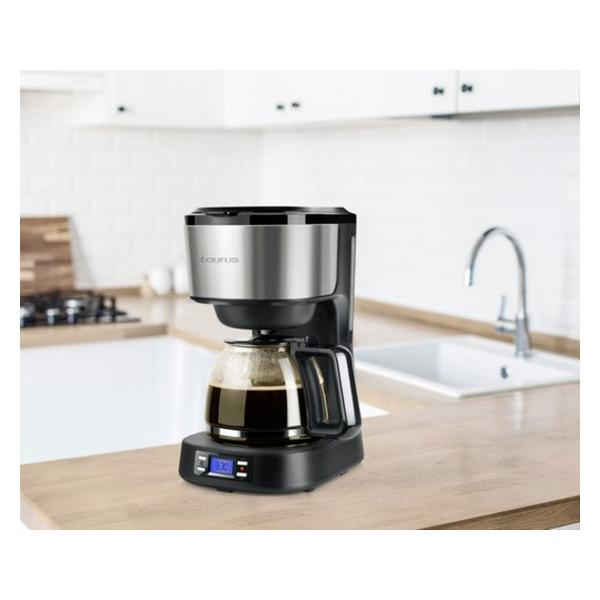 Cafetera sobre una encimera de madera. Parte superior de acero inoxidable, jarra de vidrio con café y pantalla digital.