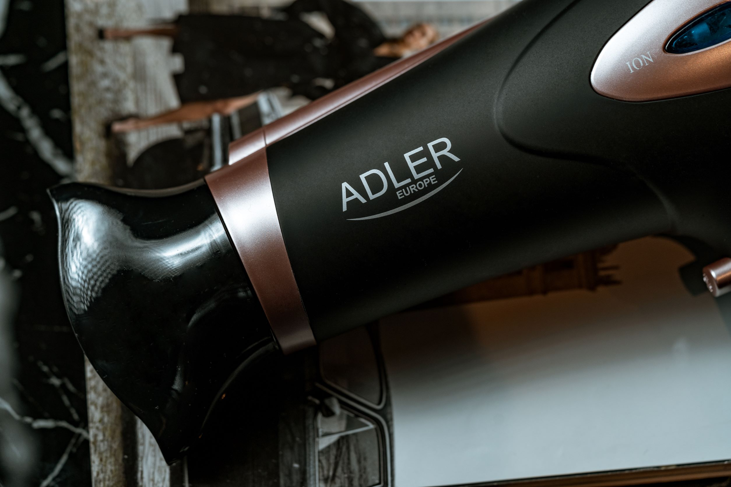 Czarna i miedziana suszarka do włosów ADLER z logo marki, ujęcie z bliska.