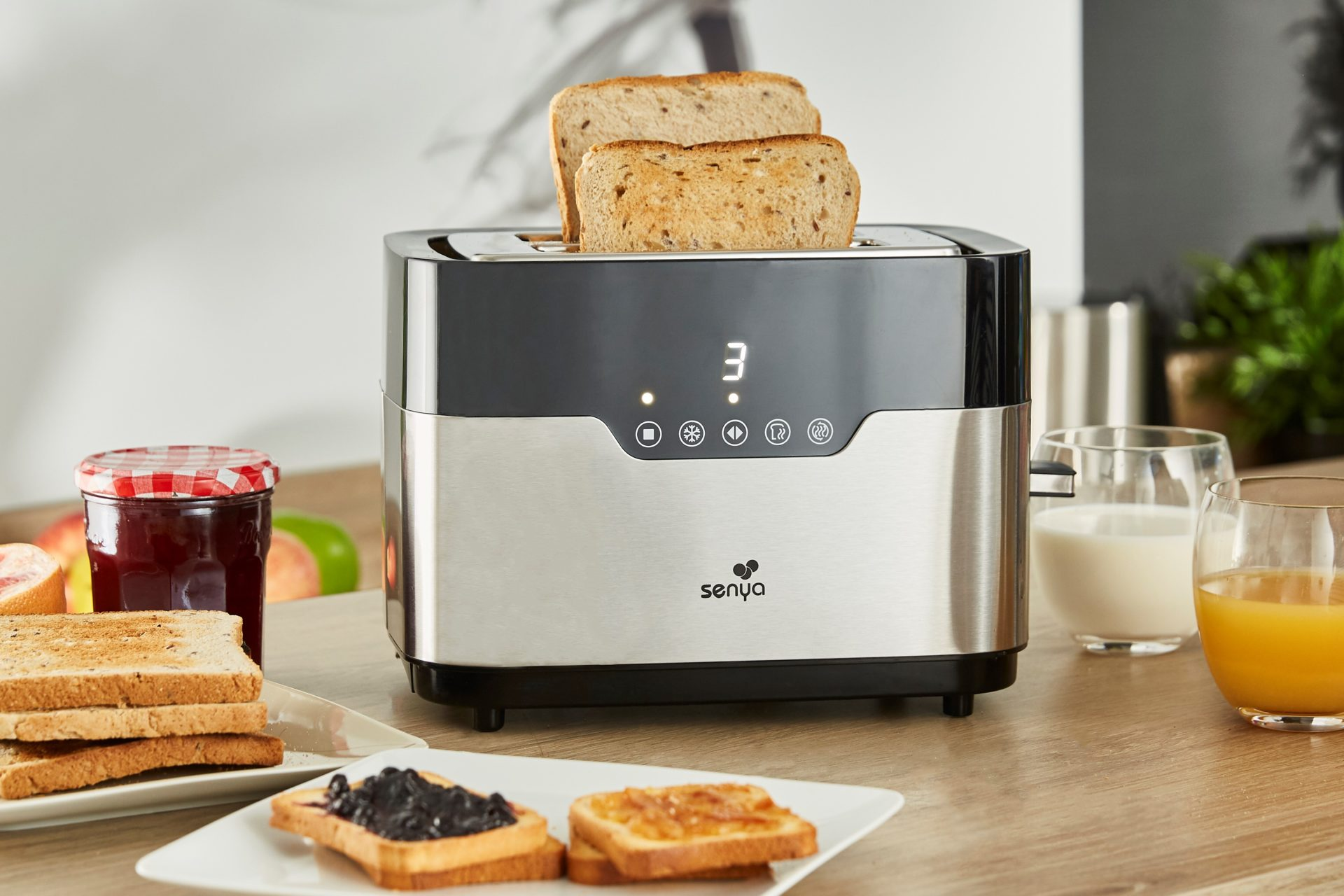 Toaster mit Brotscheiben und anderen Frühstücksartikeln auf dem Tisch.