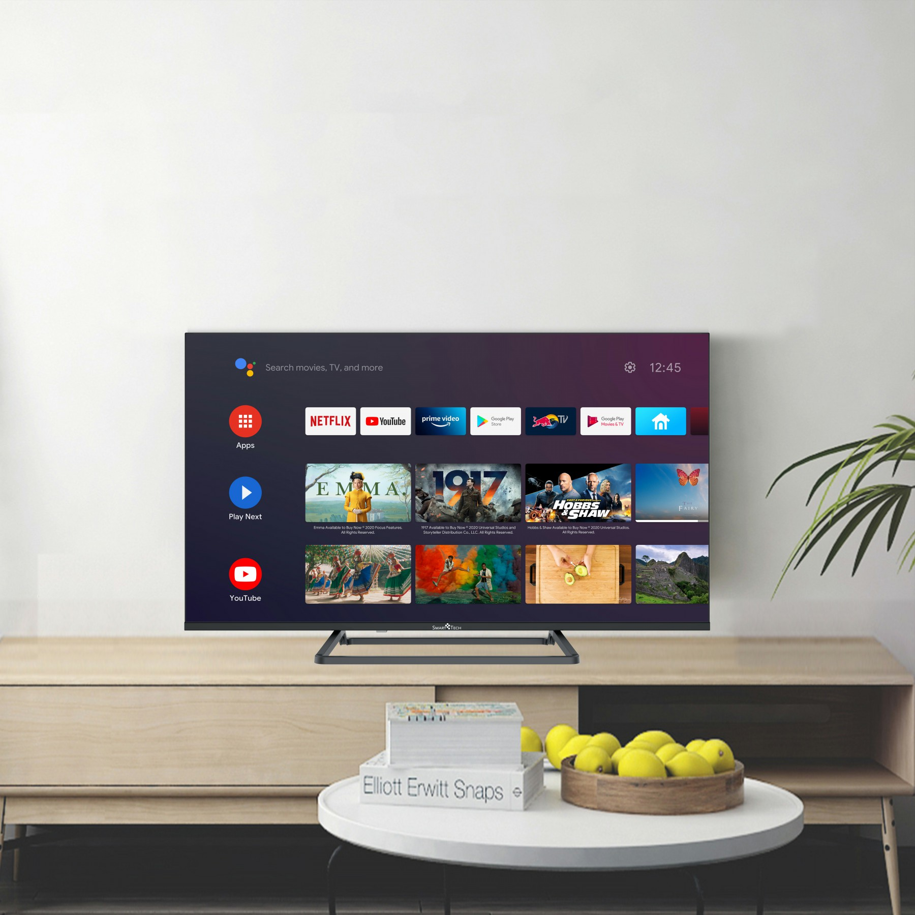 Smart-TV zeigt Apps und Inhalte. Steht auf einem Holzständer mit Büchern und einer Obstschale darunter.