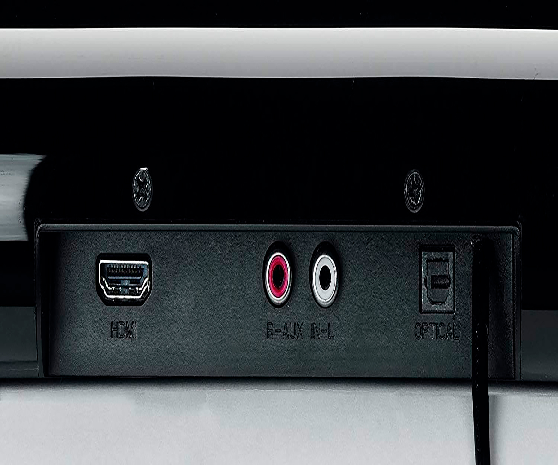 Primer plano de los puertos traseros de una barra de sonido negra. Incluye puertos HDMI, AUX y ópticos.