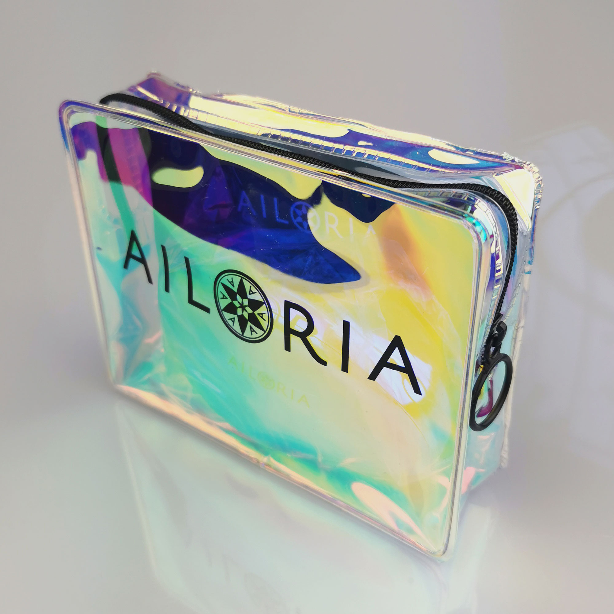 Schillernde Make-up-Tasche mit dem Wort „AILORIA“ darauf, auf weißem Hintergrund.