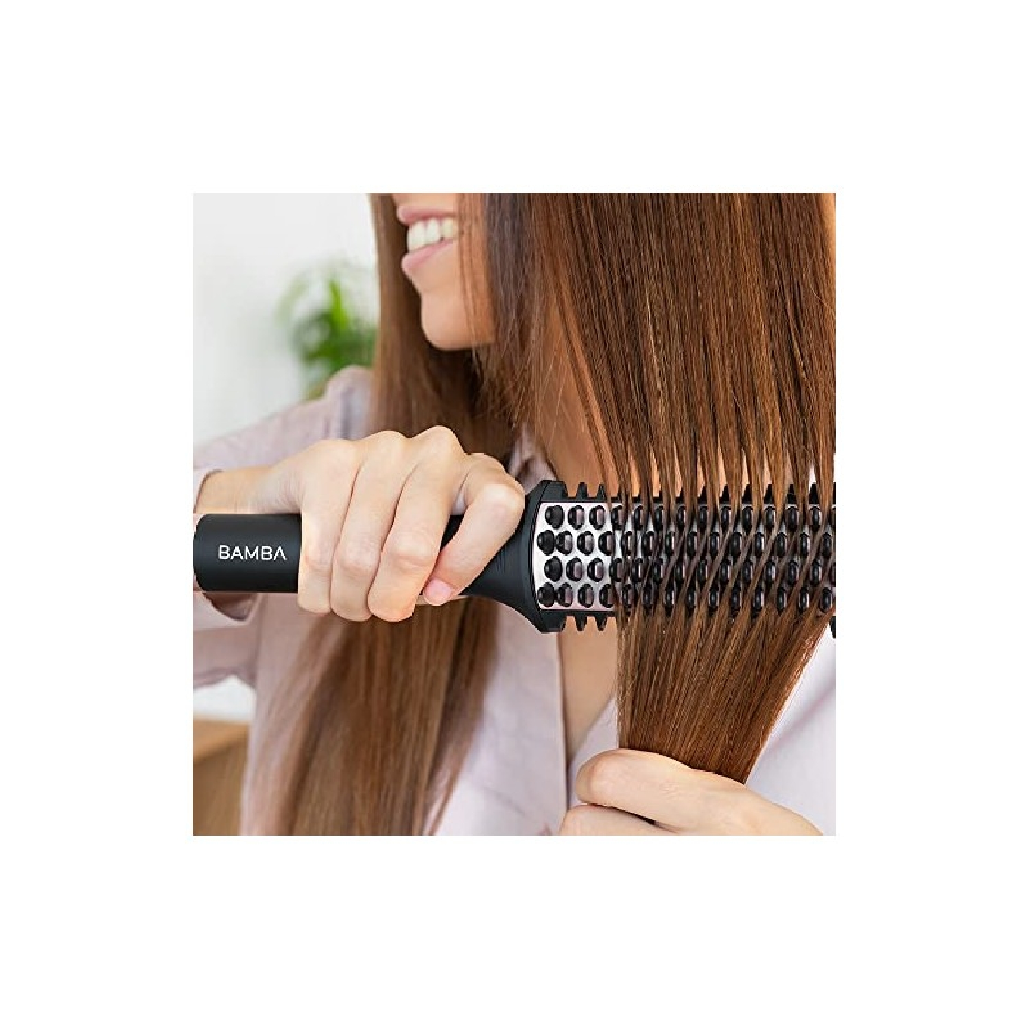 Een vrouw die haar haar borstelt met een zwarte ronde borstel. Haar hand houdt de handgreep vast.
