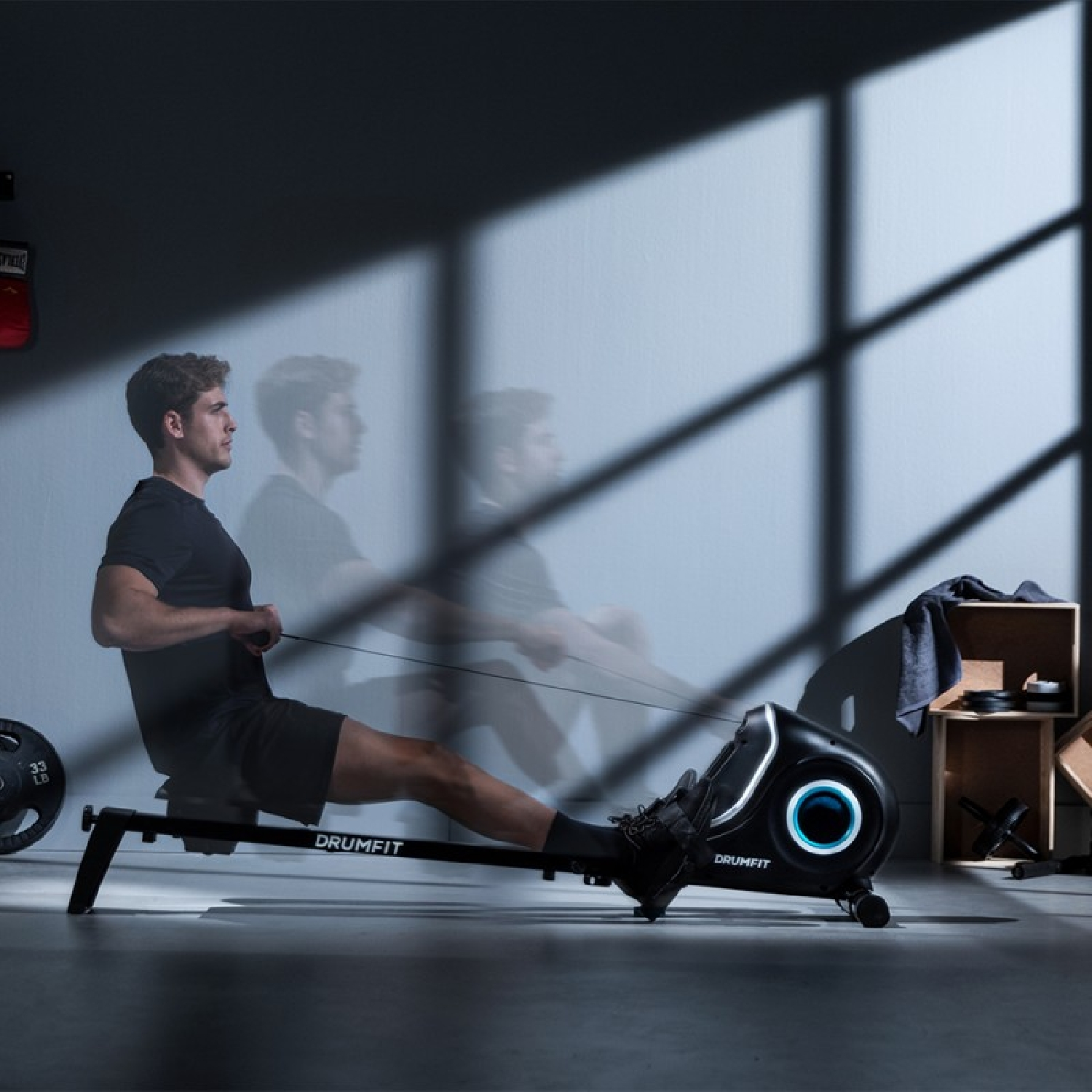 Un hombre en una máquina de remo en un gimnasio. Su acción crea un efecto de movimiento borroso.