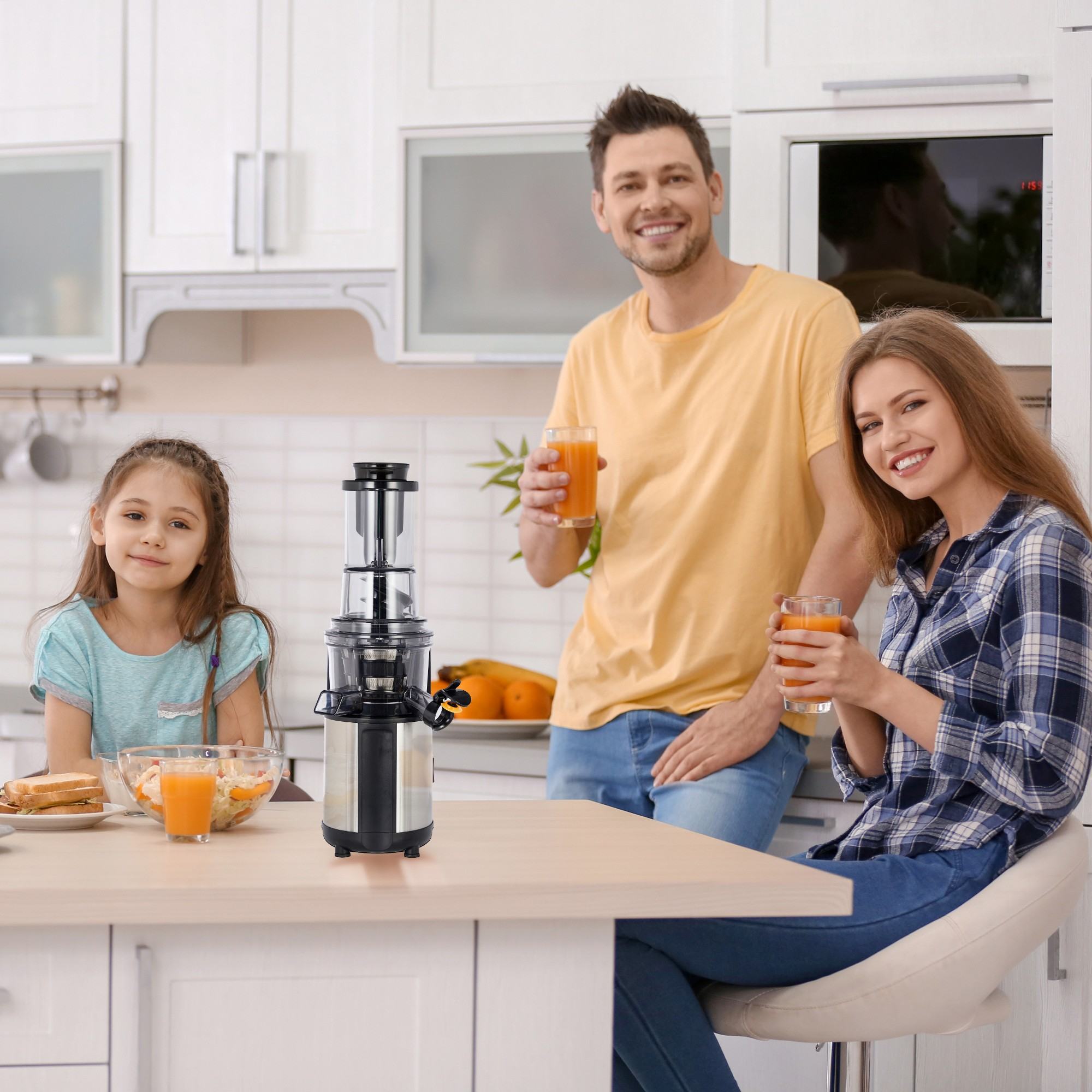 Eine Familie in der Küche. Saftpresse auf der Theke, Saft in Gläsern. Sie lächeln.