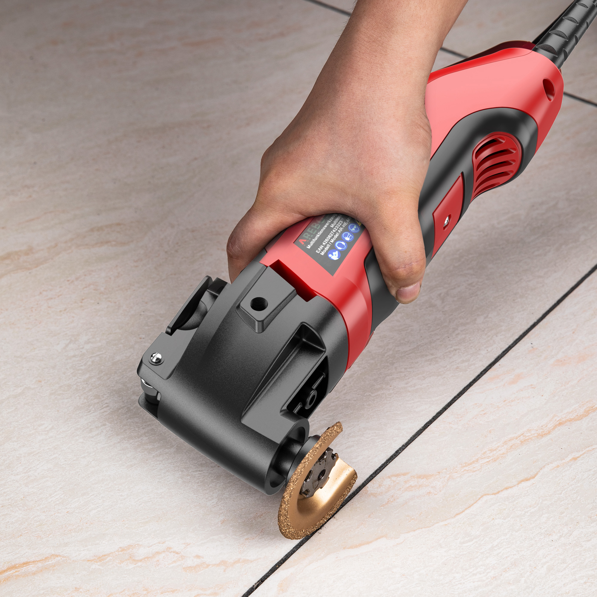 Hand, die ein rot-schwarzes Multitool auf einem Fliesenboden verwendet und die Fugen schneidet.