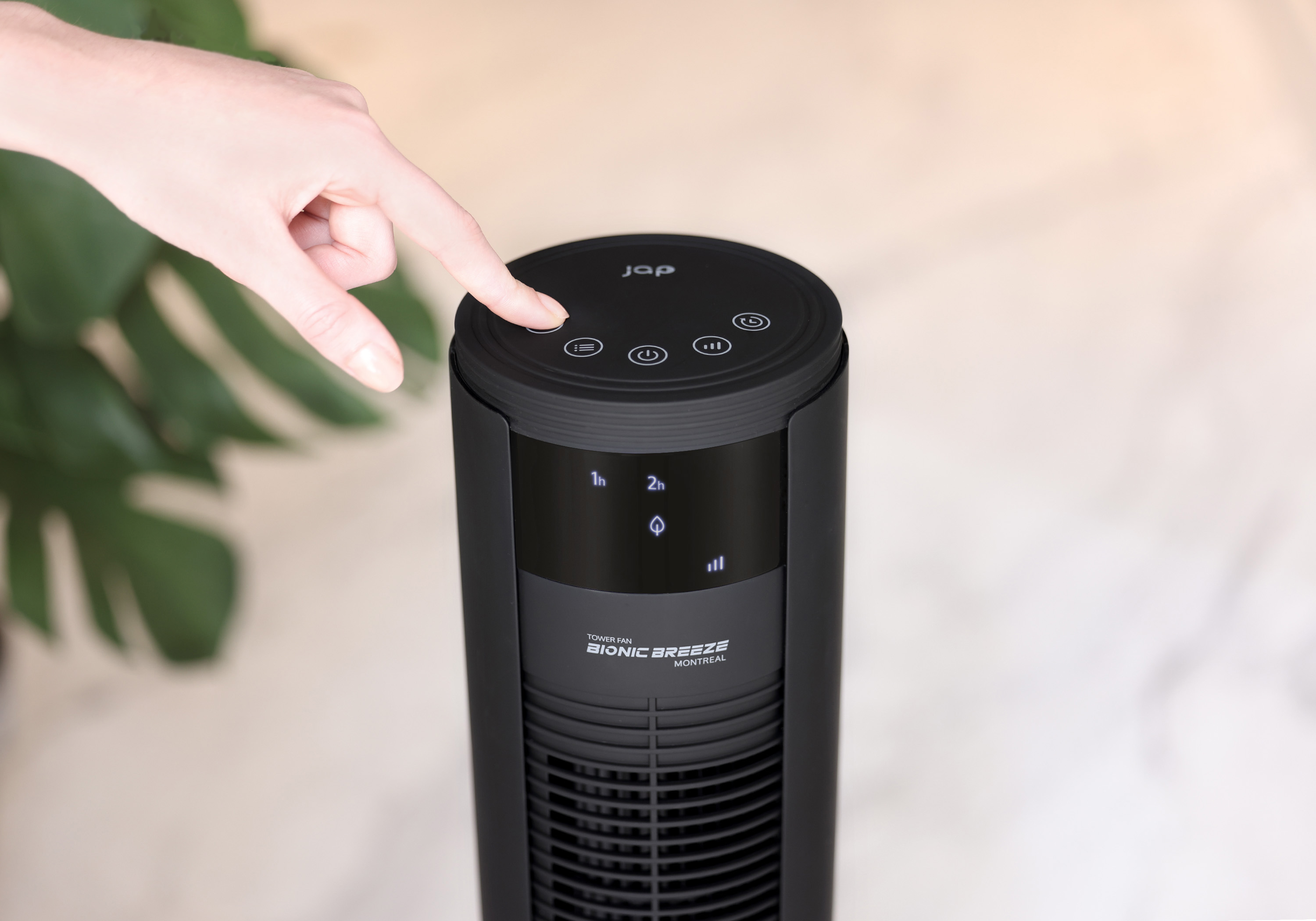 Hand drückt eine Taste an einem schwarzen Turmventilator.