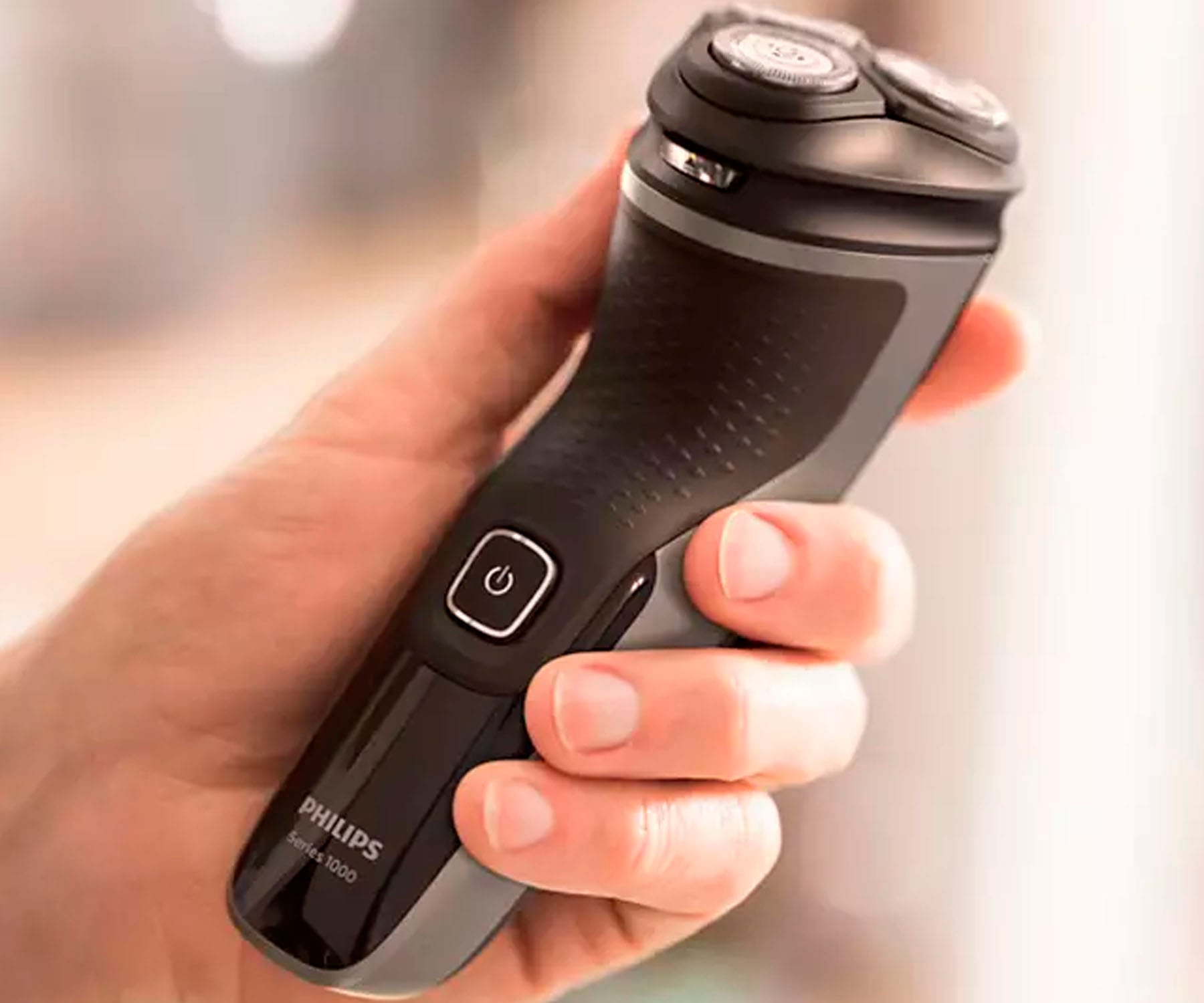 Mano che tiene un rasoio elettrico Philips nero e grigio.