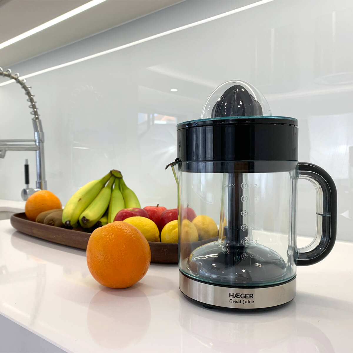Centrifuga con frutta: arance, limoni, kiwi, banane e mele disposte su un bancone.