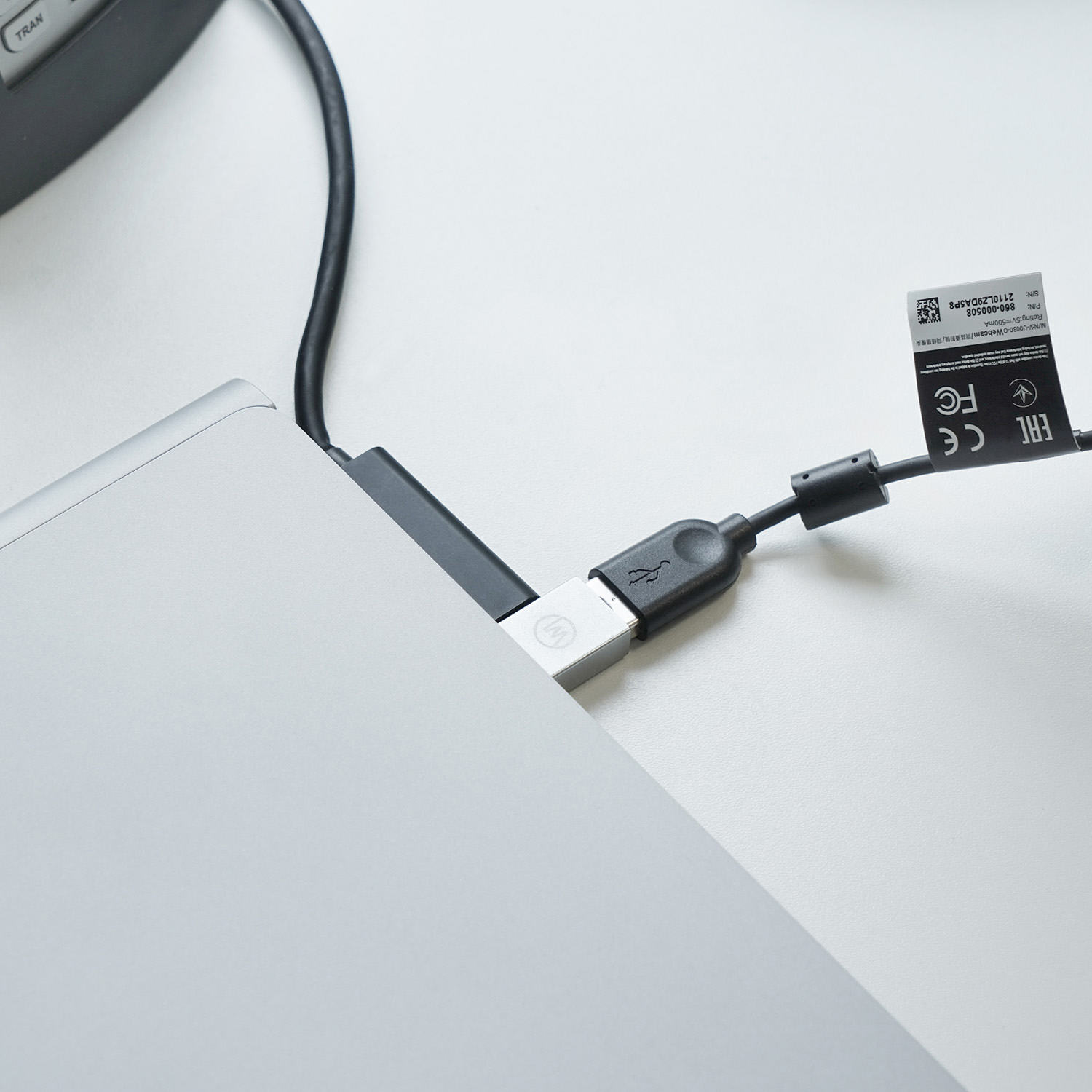 Ein USB-C-Kabel, das an einen silbernen Laptop angeschlossen ist, mit einem schwarzen Kabel und weißem Hintergrund.