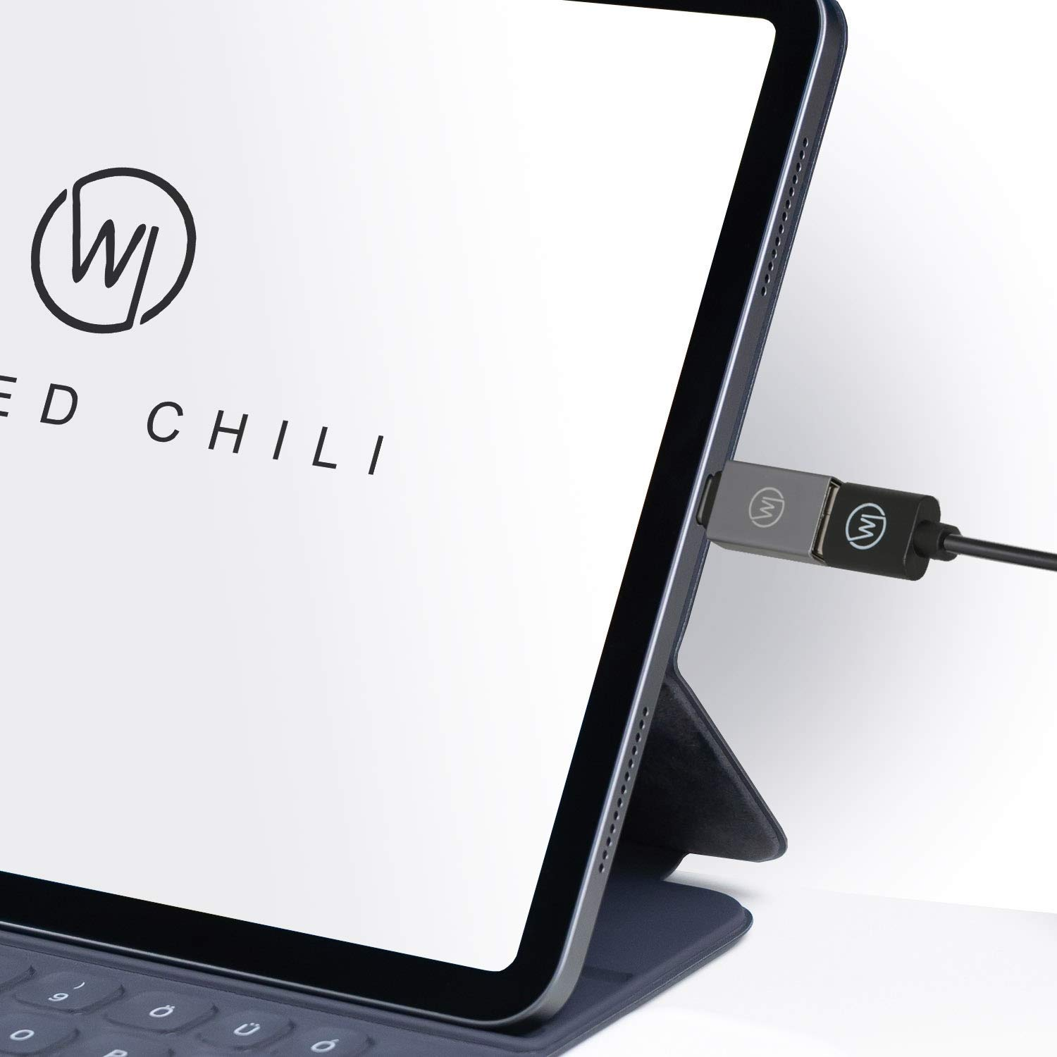 Tablet mit silbernem Adapter, eingesteckt. Der Adapter hat ein Logo.