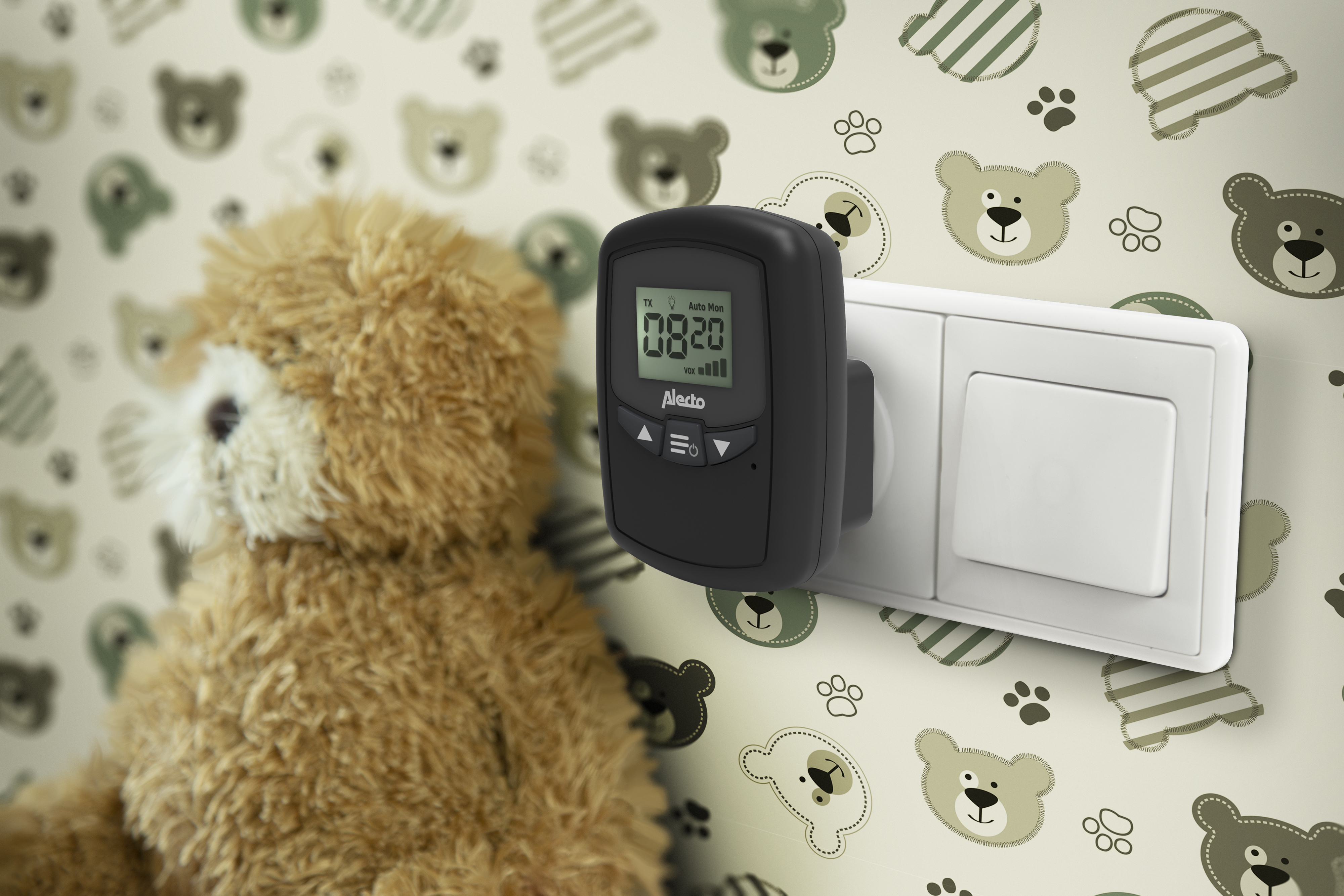 Black baby monitor plugged in, with a teddy bear in the blurry background.