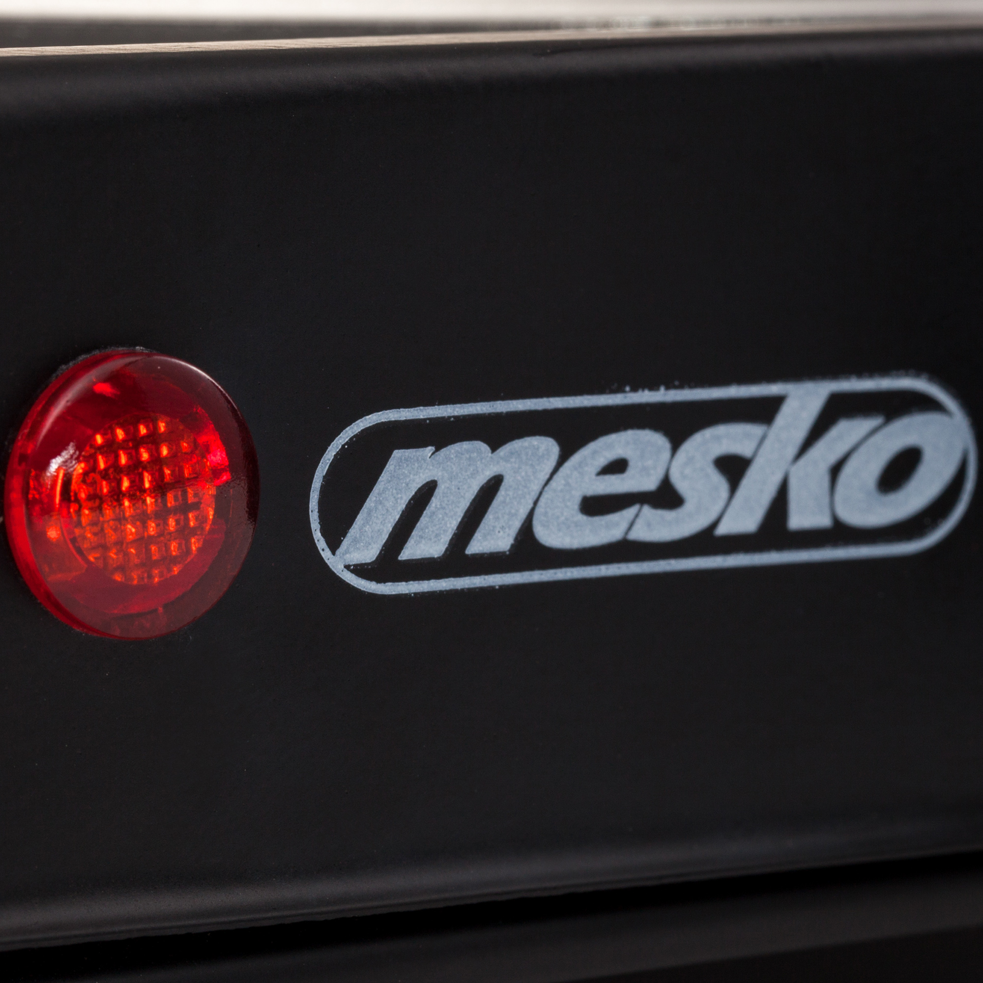 Czarne urządzenie z czerwonym światłem i napisem "mesko".