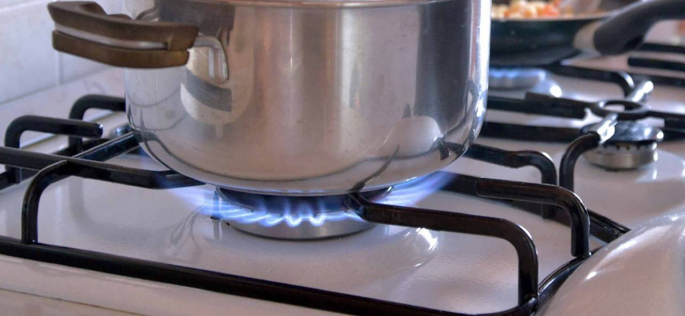 Una olla de acero inoxidable en una estufa con llamas azules.